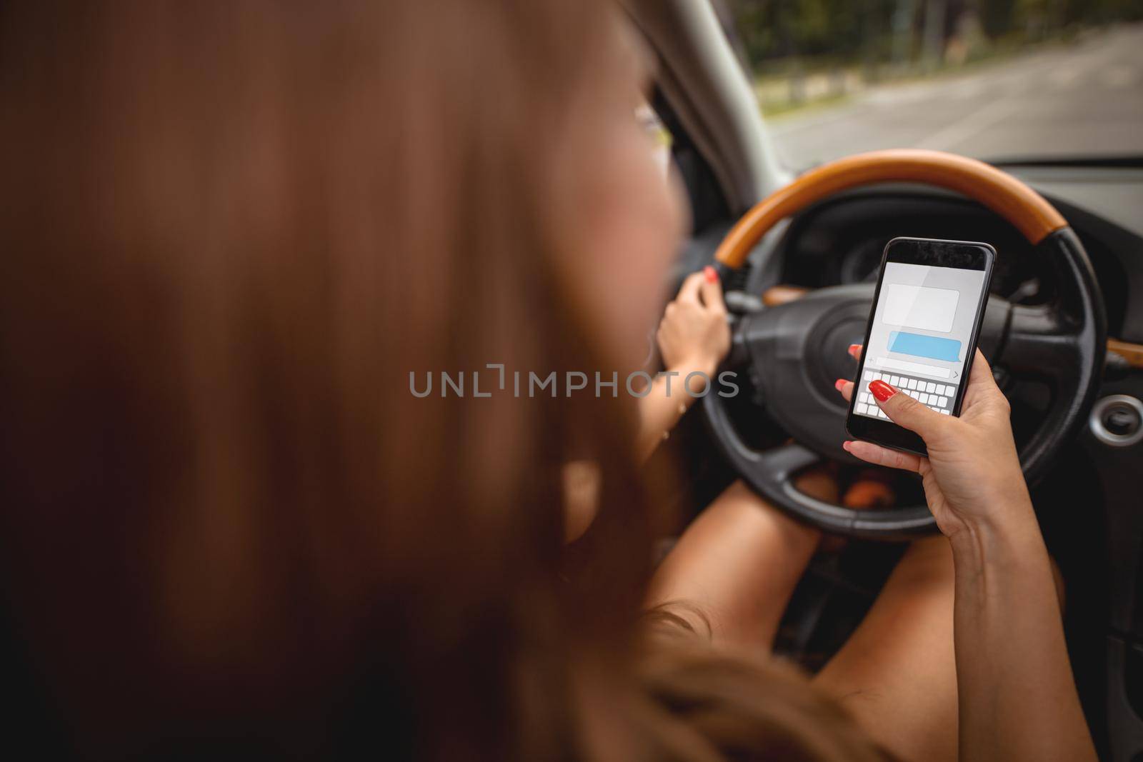Woman texting on smartphone while driving a car.