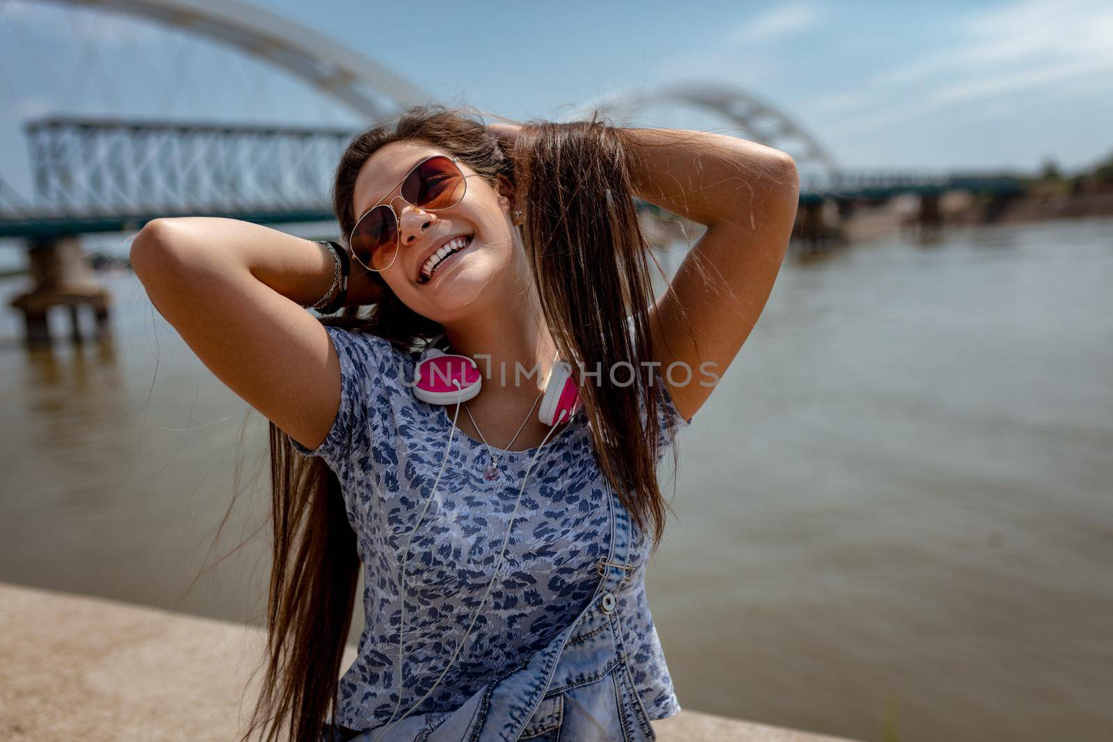 A beautiful cheerful gir having fun with your hair in the open and enjoying on the city rivershore on a beautiful summer day.