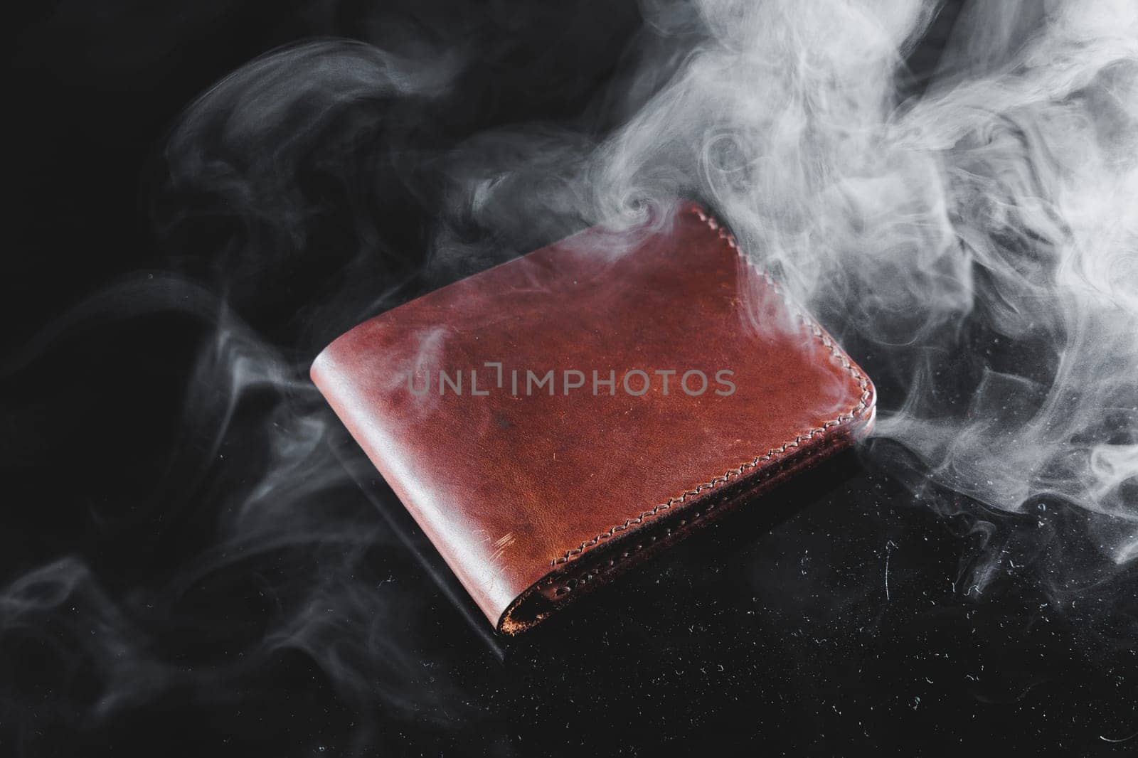 Stylish handmade brown leather wallet on a gray background. Product made of genuine leather.