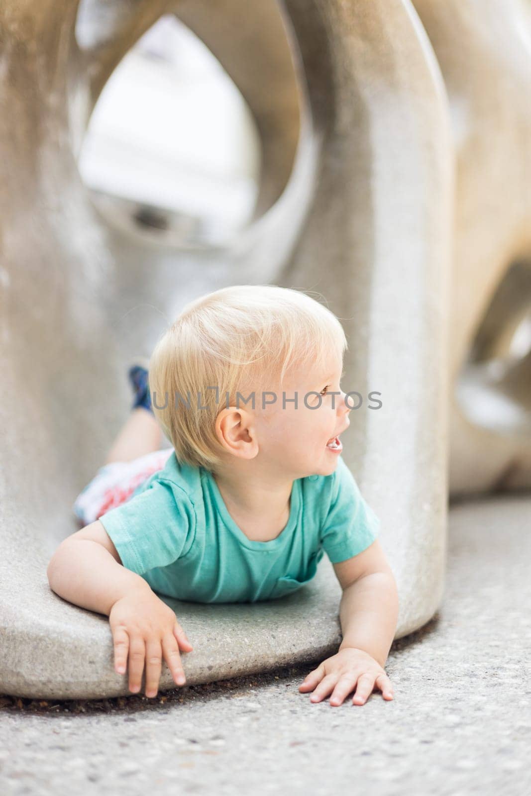 Child playing on outdoor playground. Toddler plays on school or kindergarten yard. Active kid on stone sculpured slide. Healthy summer activity for children. Little boy climbing outdoors