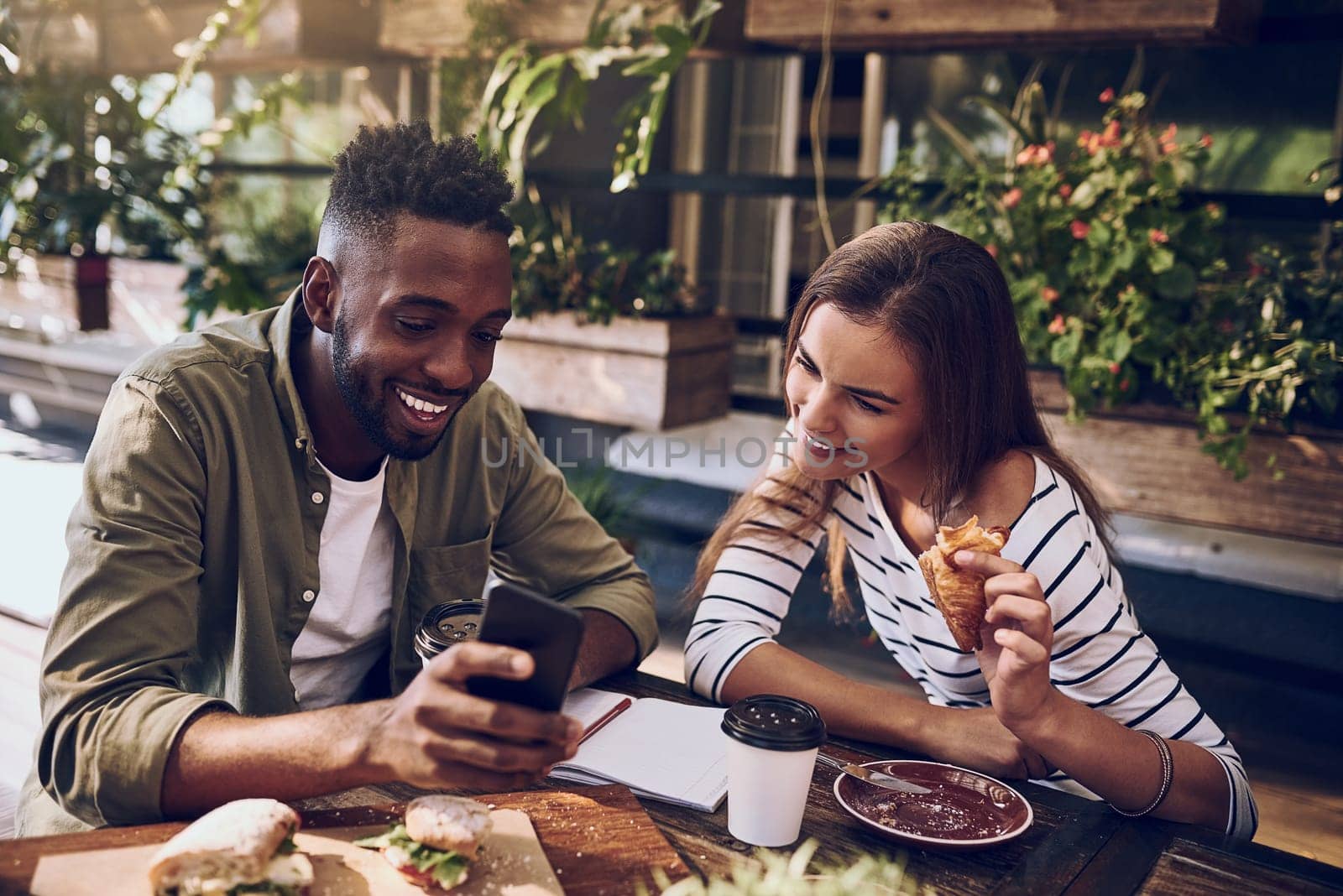 Restaurant, happy and black man and woman with phone for social media, internet and online website. Coffee shop, communication and friends on smartphone laugh at meme, talking and chat at breakfast by YuriArcurs