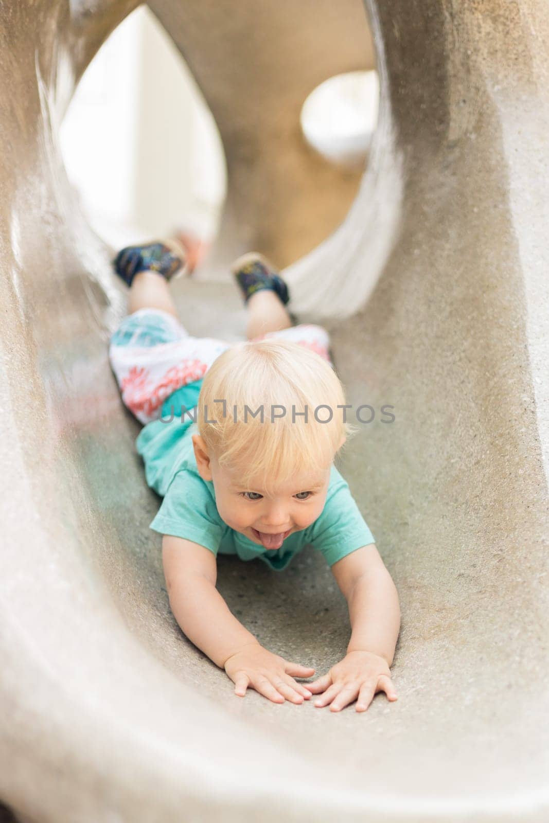 Child playing on outdoor playground. Toddler plays on school or kindergarten yard. Active kid on stone sculpured slide. Healthy summer activity for children. Little boy climbing outdoors. by kasto