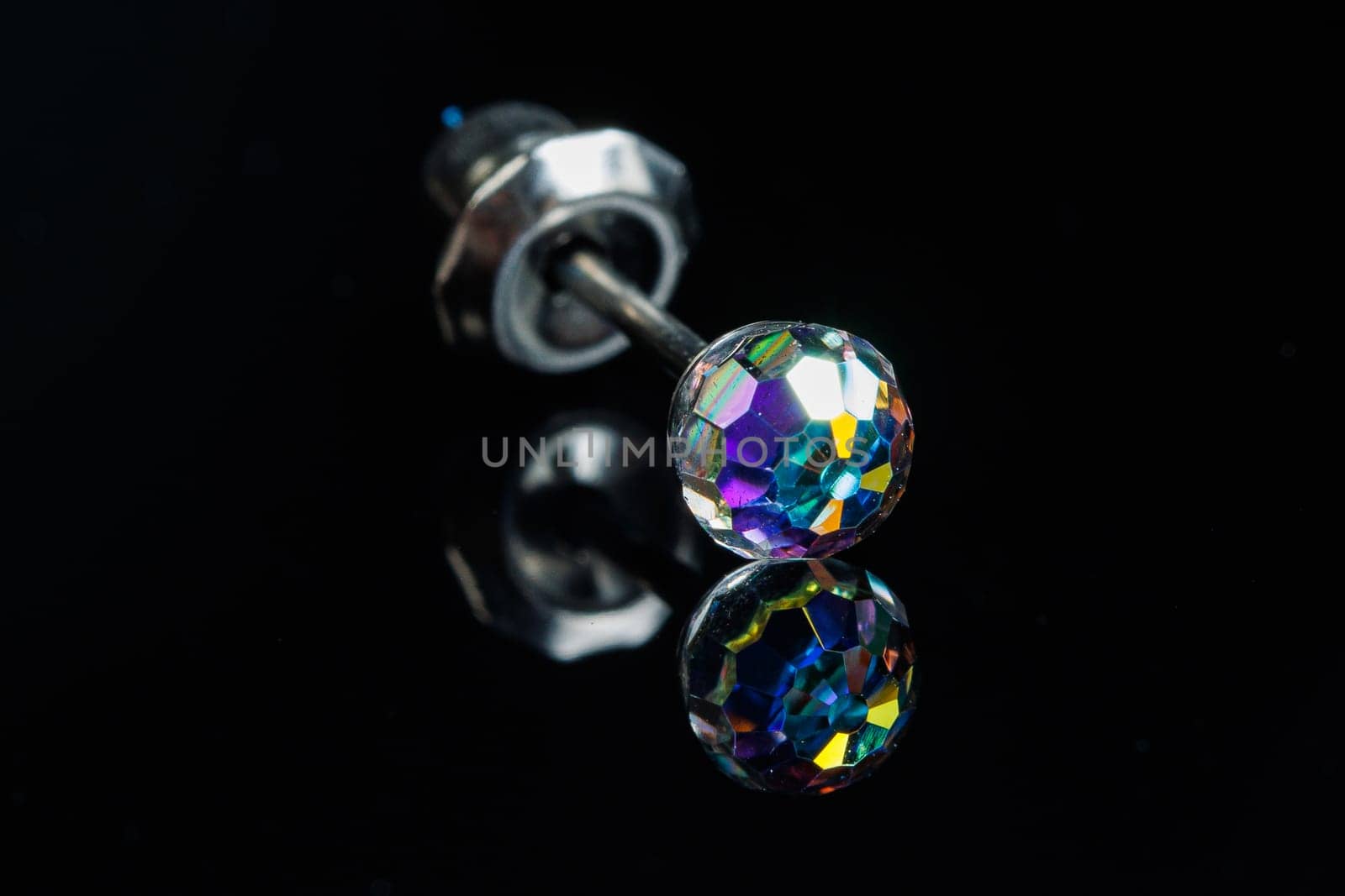 Silver earring macro photo with a precious stone on a black isolated background