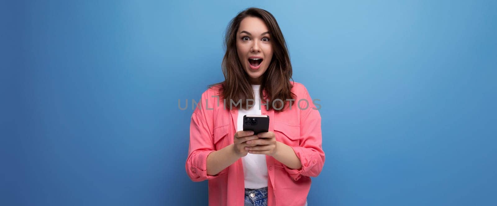 portrait of cute long haired young woman surfing online using smartphone and isolated studio background.