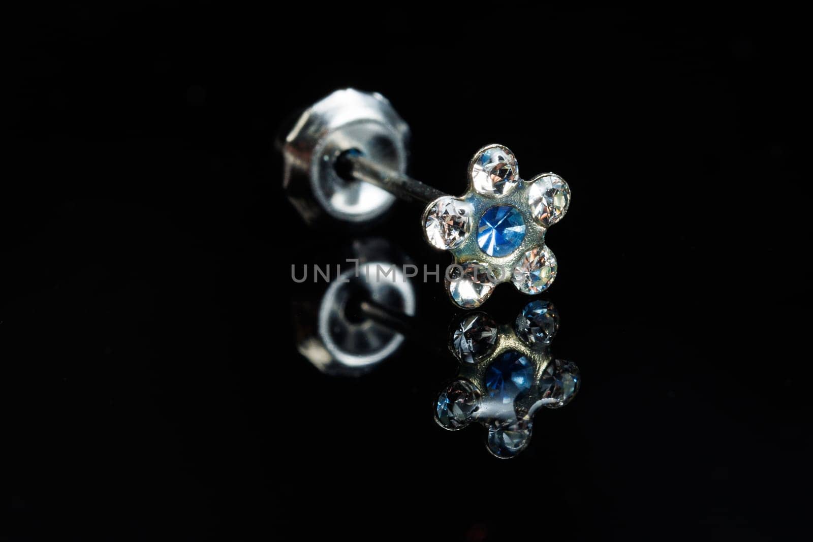 Jewelry with stone earrings, luxury silver earrings with diamonds, sapphires on a black background. Selective focus.