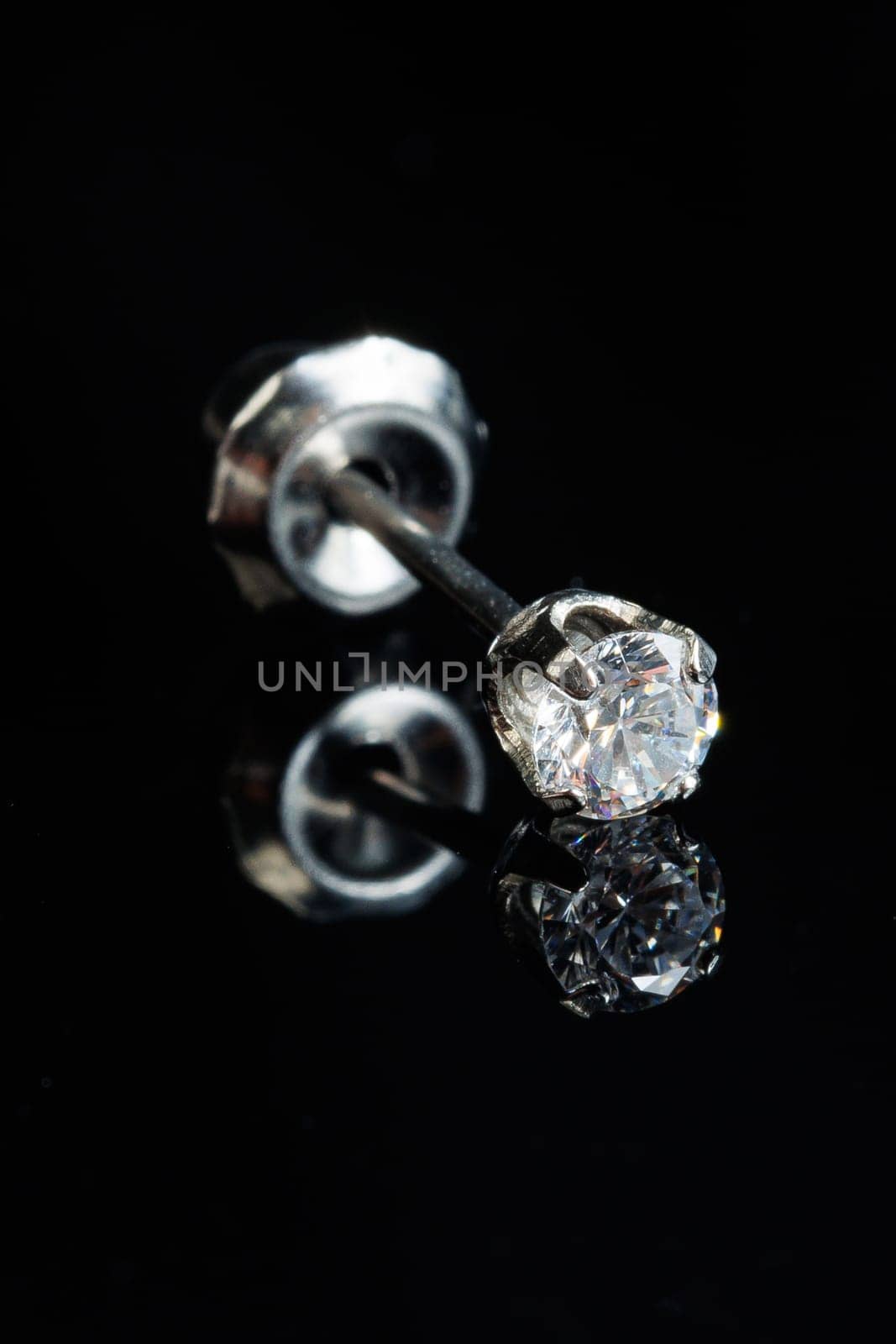 Silver earring macro photo with a precious stone on a black isolated background