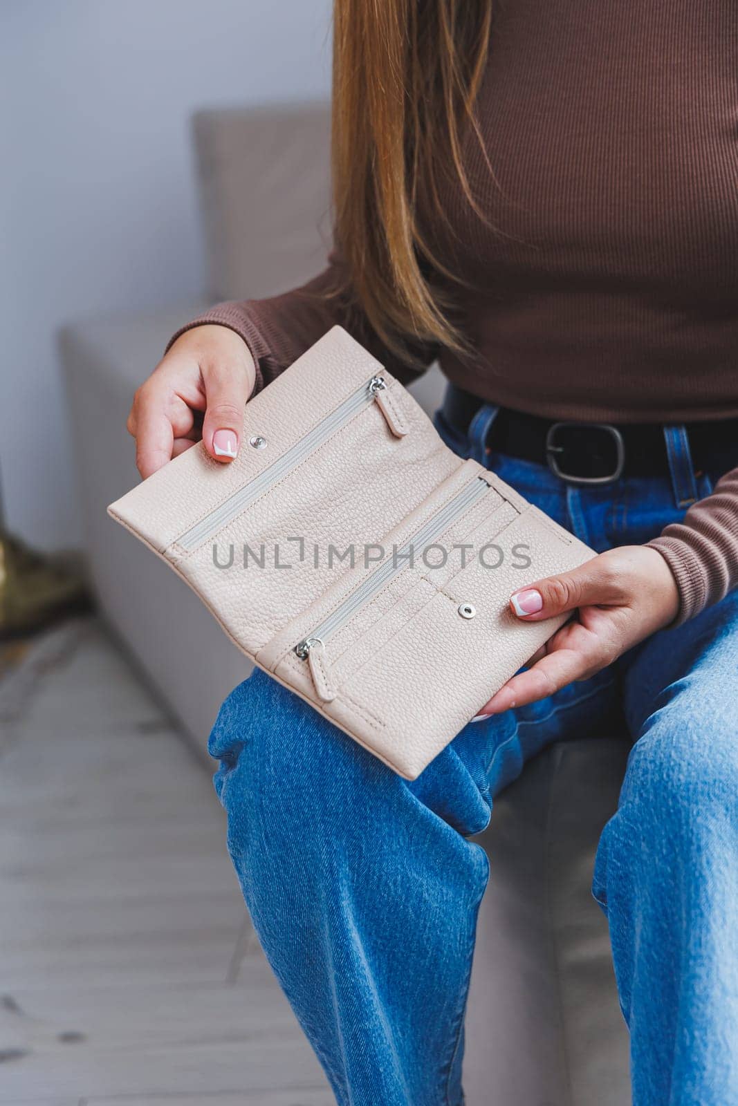 A beautiful woman holds a beige leather purse in her hands. Small women's handbag