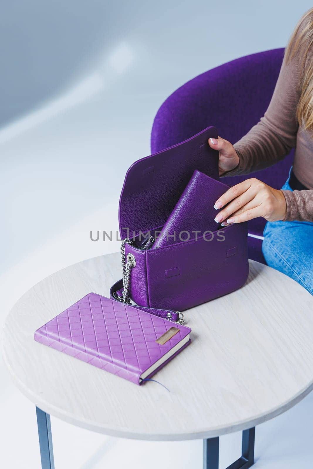 A purple leather bag in a girl's hand. Woman with luxury bag.