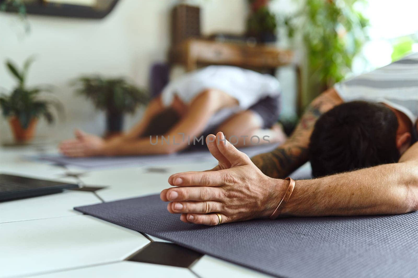 Home is where your yoga mat is. two men going through a yoga routine at home. by YuriArcurs