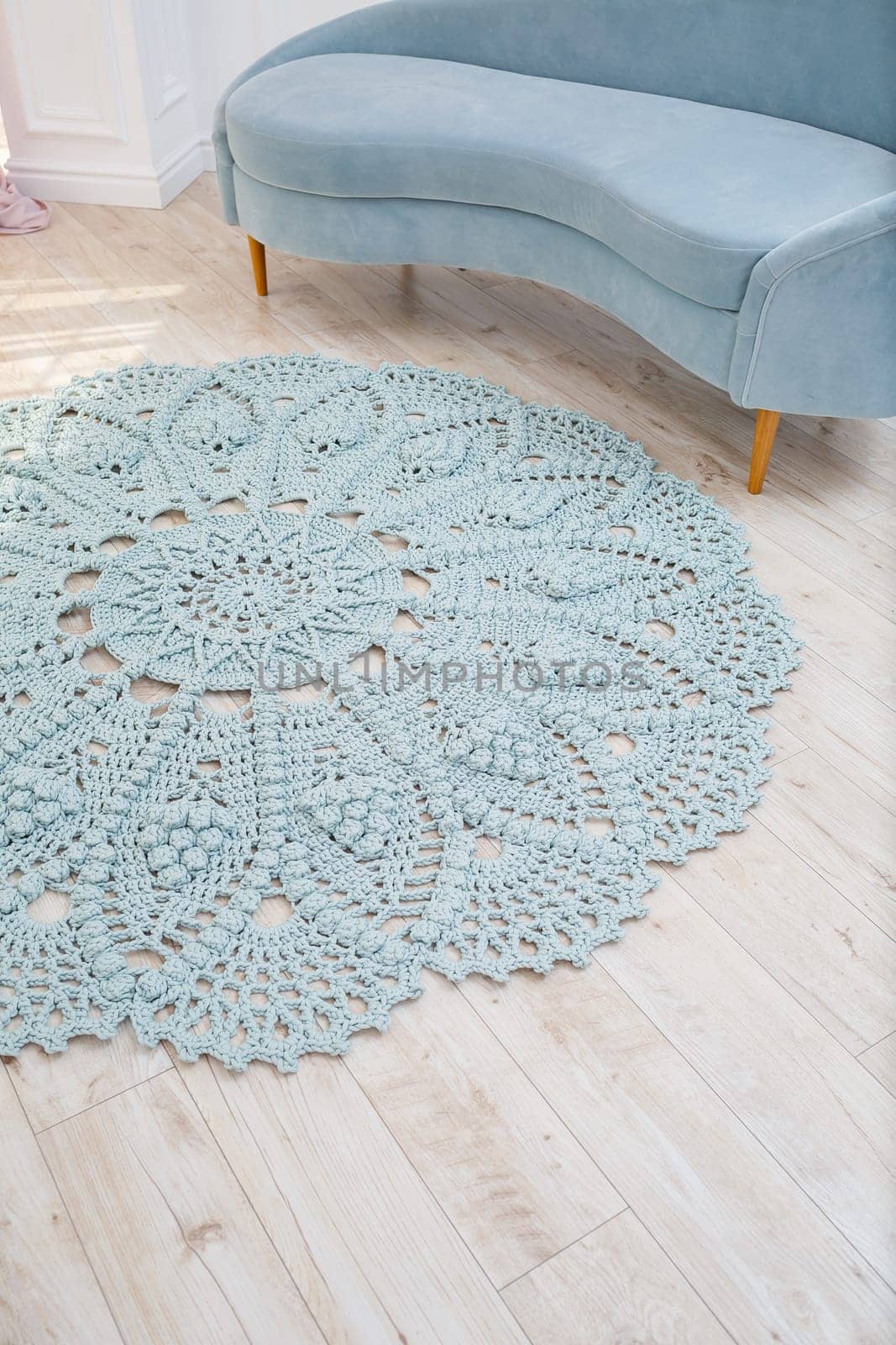 In a bright room on the floor there is a round blue handmade carpet. flooring, natural cotton. Blue knitted handmade carpet on the floor