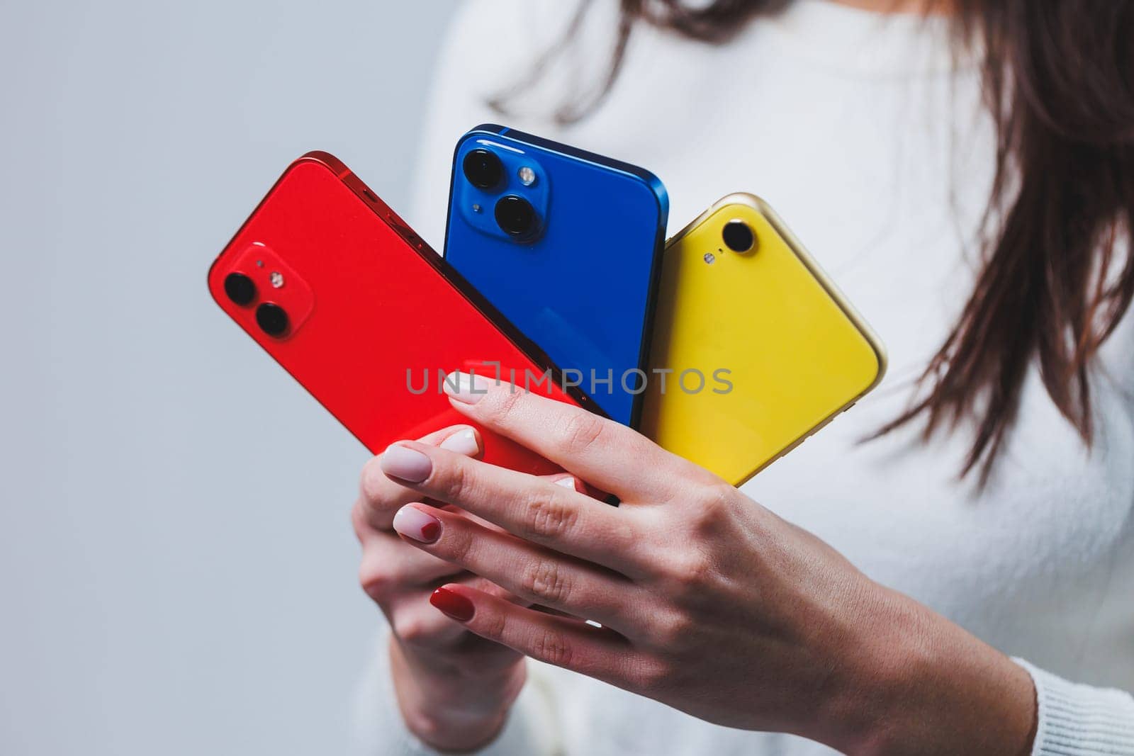 New bright phones in the hands of a woman. Hands of a woman holding several smartphones.