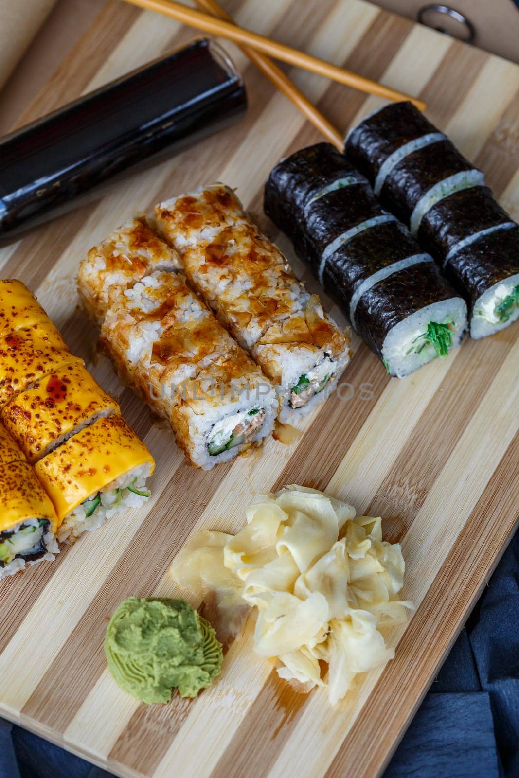 Sushi set with different types of rolls and sashimi made from eel, salmon, tuna, shrimp, red caviar and tobiko flying fish roe. Pan-Asian and Asian food and dishes on a black concrete kitchen table.