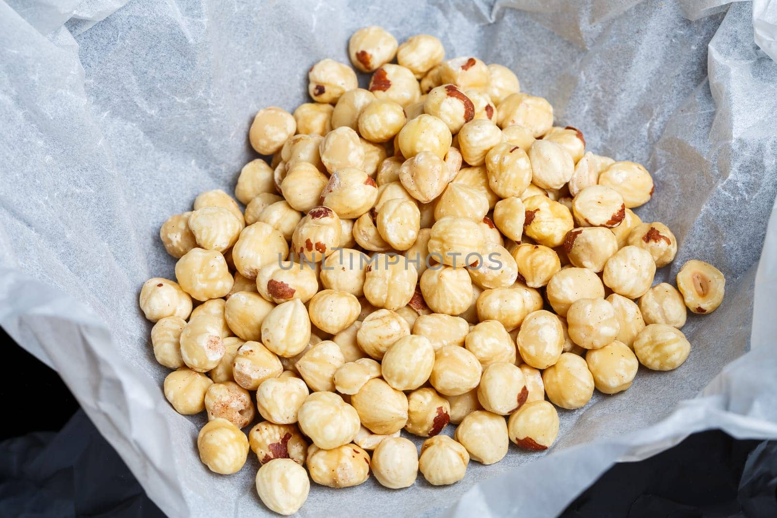 Delicious fried crispy hazelnuts lies in a heap, nuts close-up.