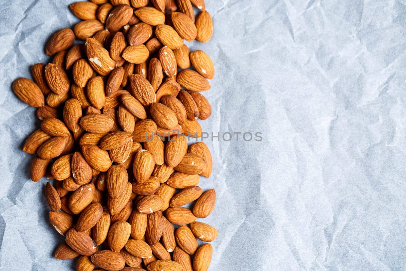 Delicious roasted sweet almonds lie in a large heap, nuts close-up.