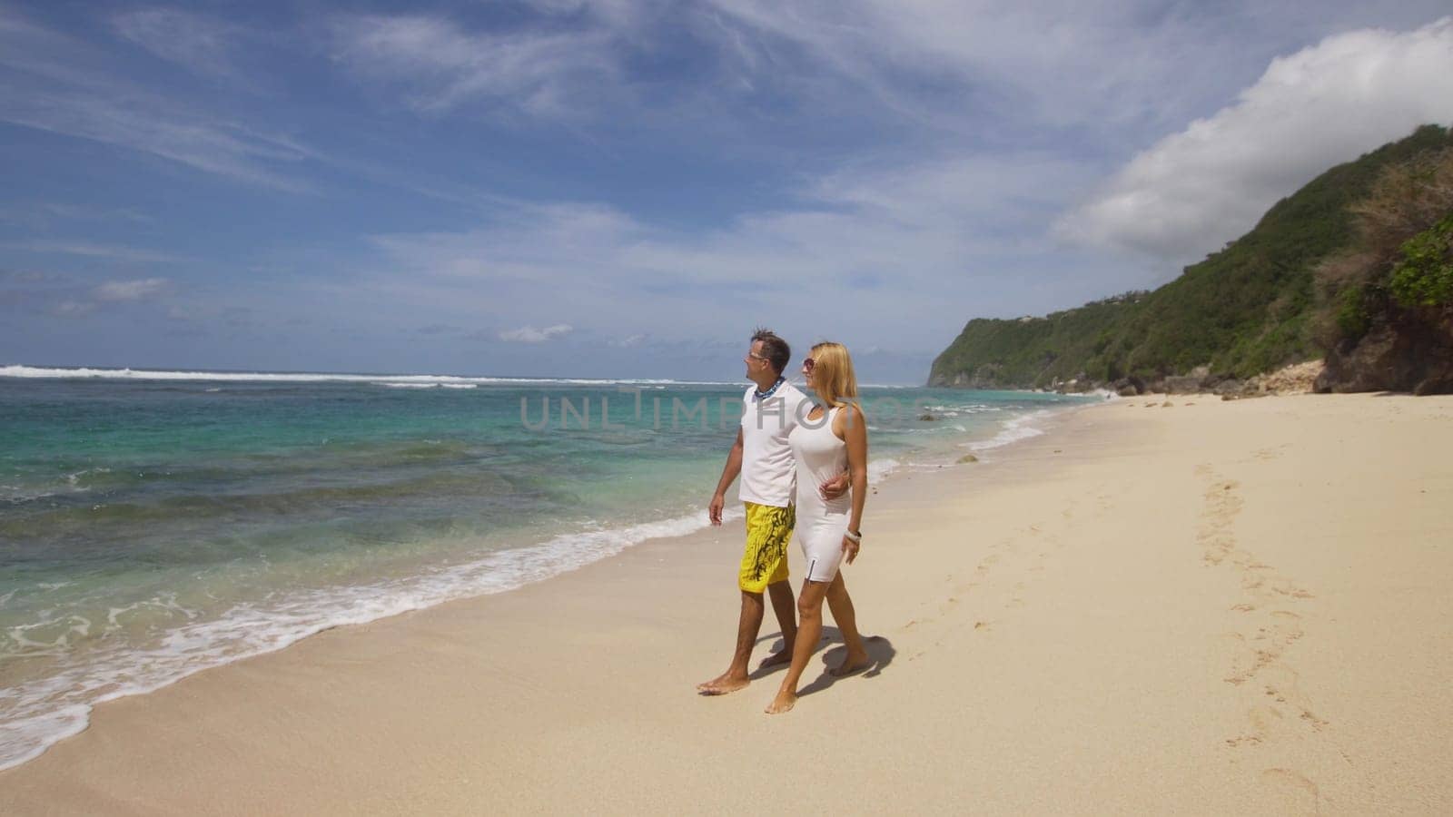 Beautiful couple embracing each other stands on the beach and looks at the sea.Relationships, Beach, couple on romantic travel honeymoon vacation summer holidays romance. Young happy lovers. Travel concept. Bali.