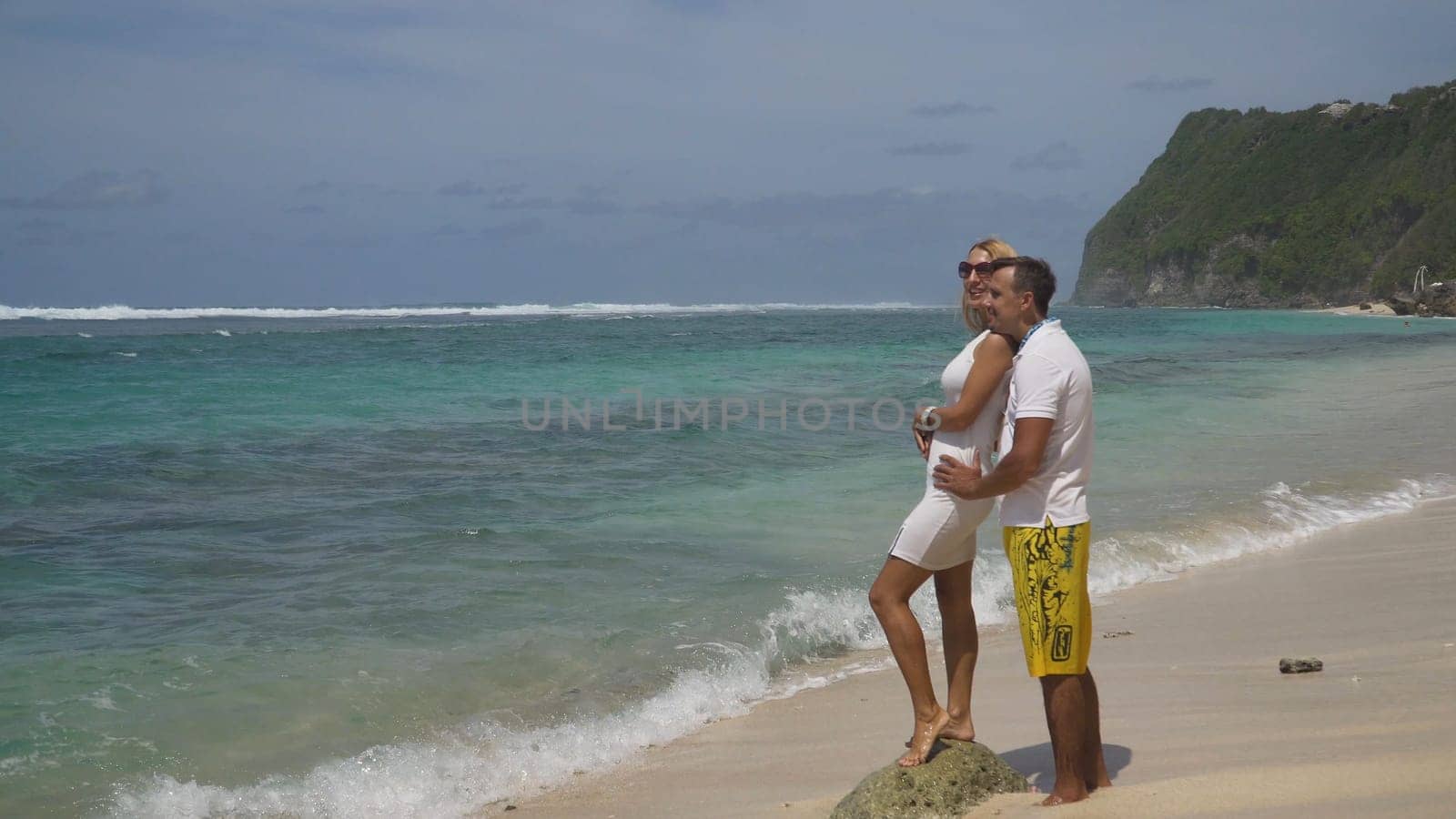 Beautiful couple embracing each other stands on the beach and looks at the sea.Relationships, Beach, couple on romantic travel honeymoon vacation summer holidays romance. Young happy lovers. Travel concept. Bali.