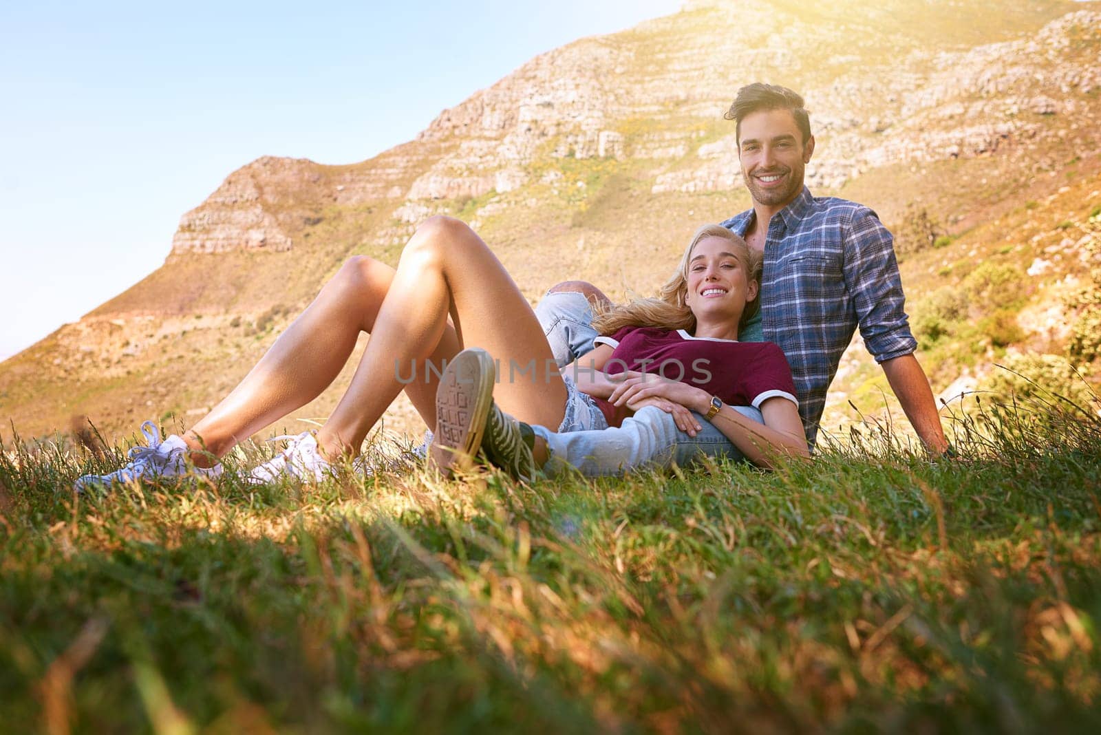 Relax, love and portrait of couple in nature for carefree, bonding and affectionate. Happiness, date and romance with man and woman cuddle in grass field for summer break, happy and mountains.