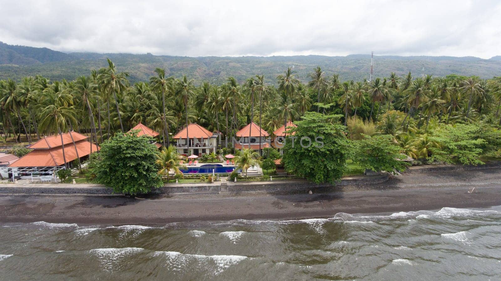 Aerial view of beautiful beach, hotel, Bali, Indonesia. Beach with black volcanic sand.Seascape ocean, sky, sea. 4K video Travel concept, Aerial footage.