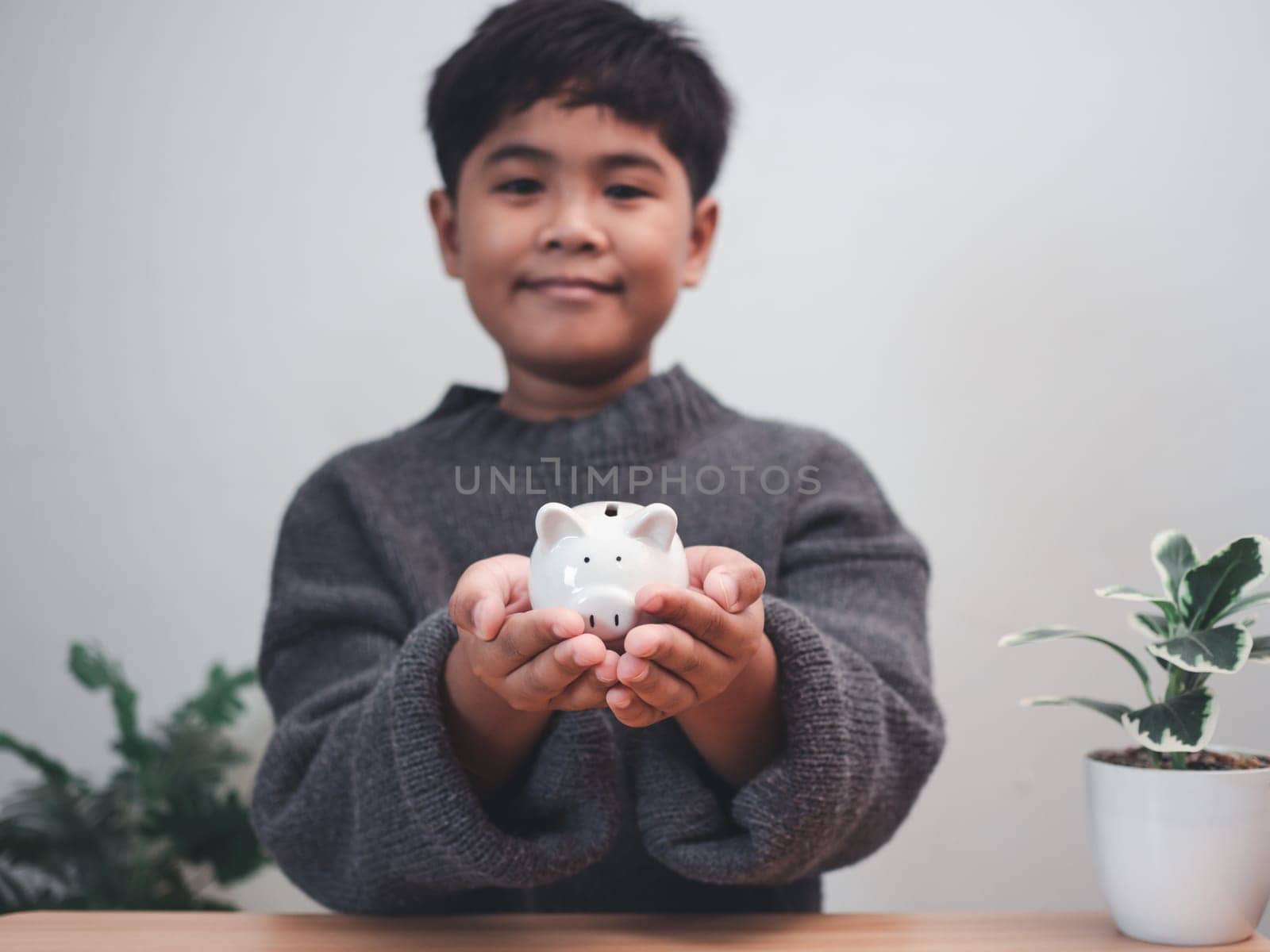 A boy holding piggy bank. Learning financial responsibility and projecting savings. savings concept. investment concept. by Unimages2527