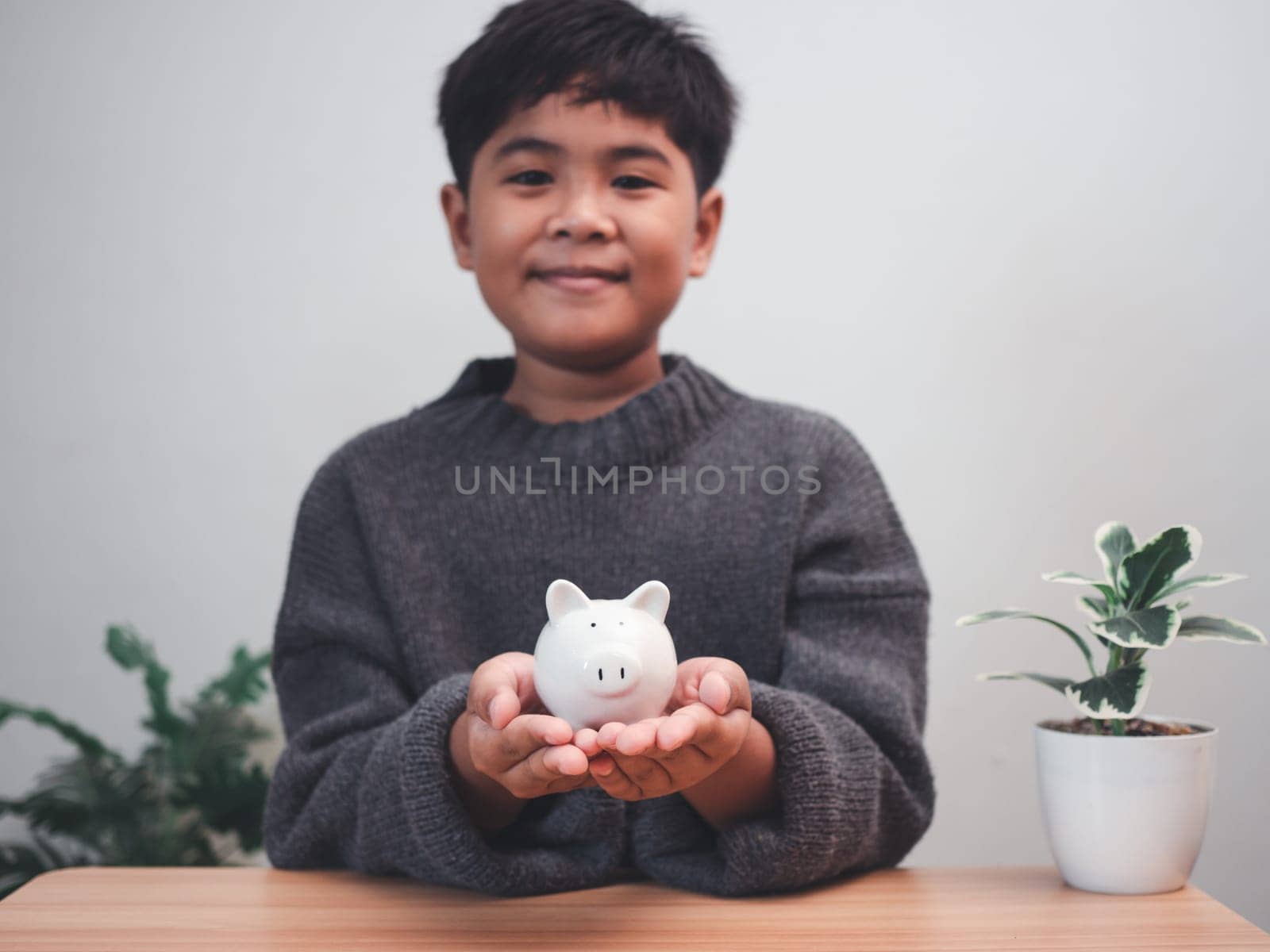 A boy holding piggy bank. Learning financial responsibility and projecting savings. savings concept. investment concept. by Unimages2527