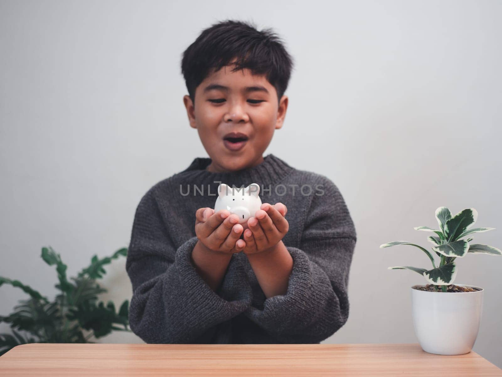 A boy holding piggy bank. Learning financial responsibility and projecting savings. savings concept. investment concept. by Unimages2527