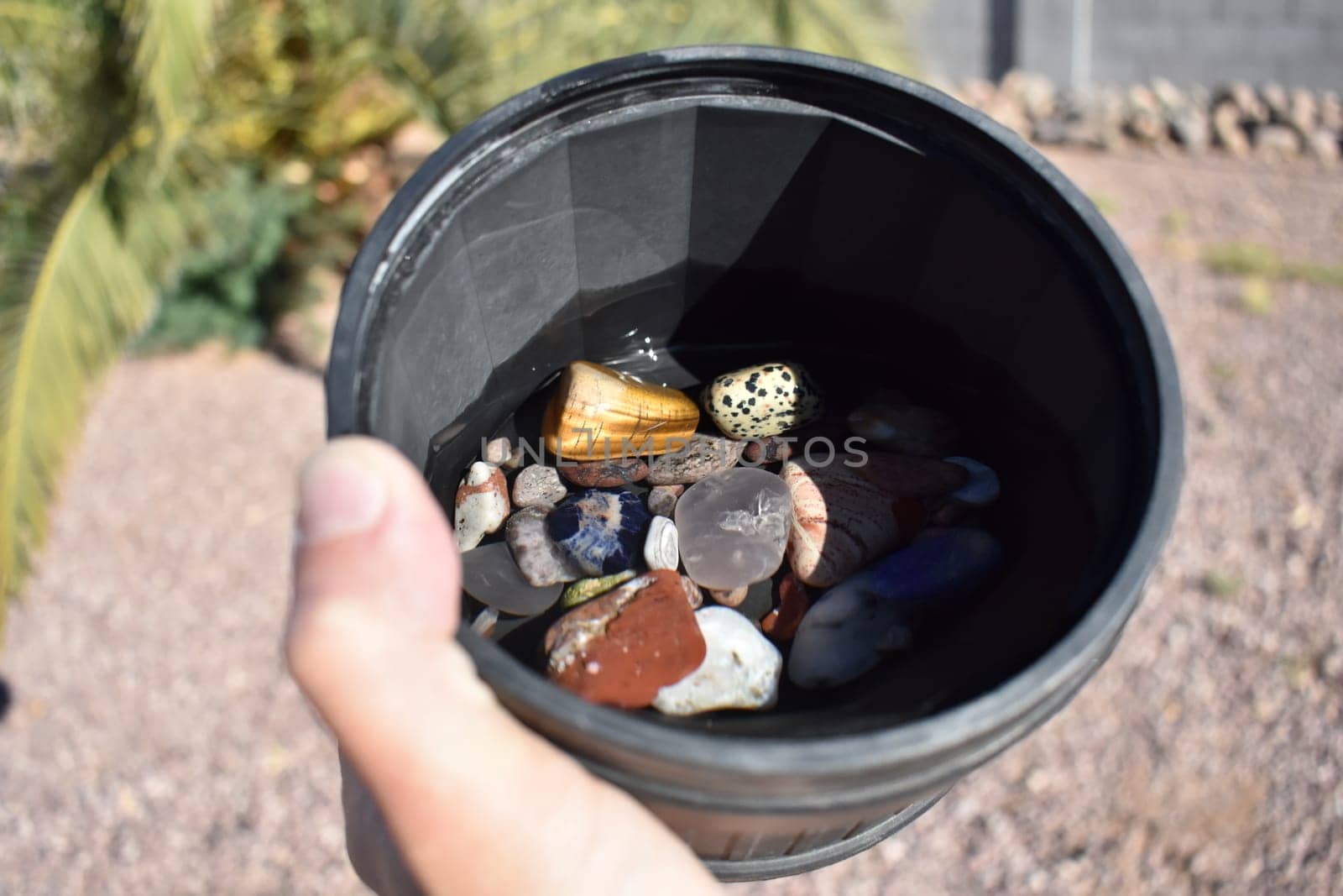 Hand Holding Rock Tumbler Barrel Full of Assorted Polished Stones by grumblytumbleweed