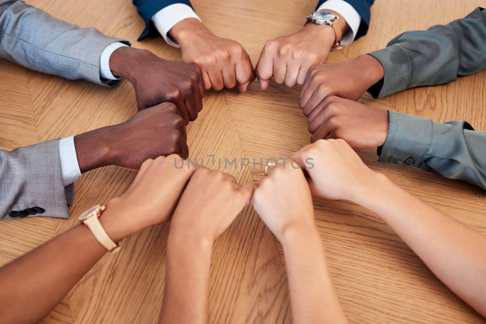 Diversity, teamwork and circle of hands in fist, aerial view for support, community and unity in workplace. Collaboration, agreement and business people working together in meeting with hand on desk.