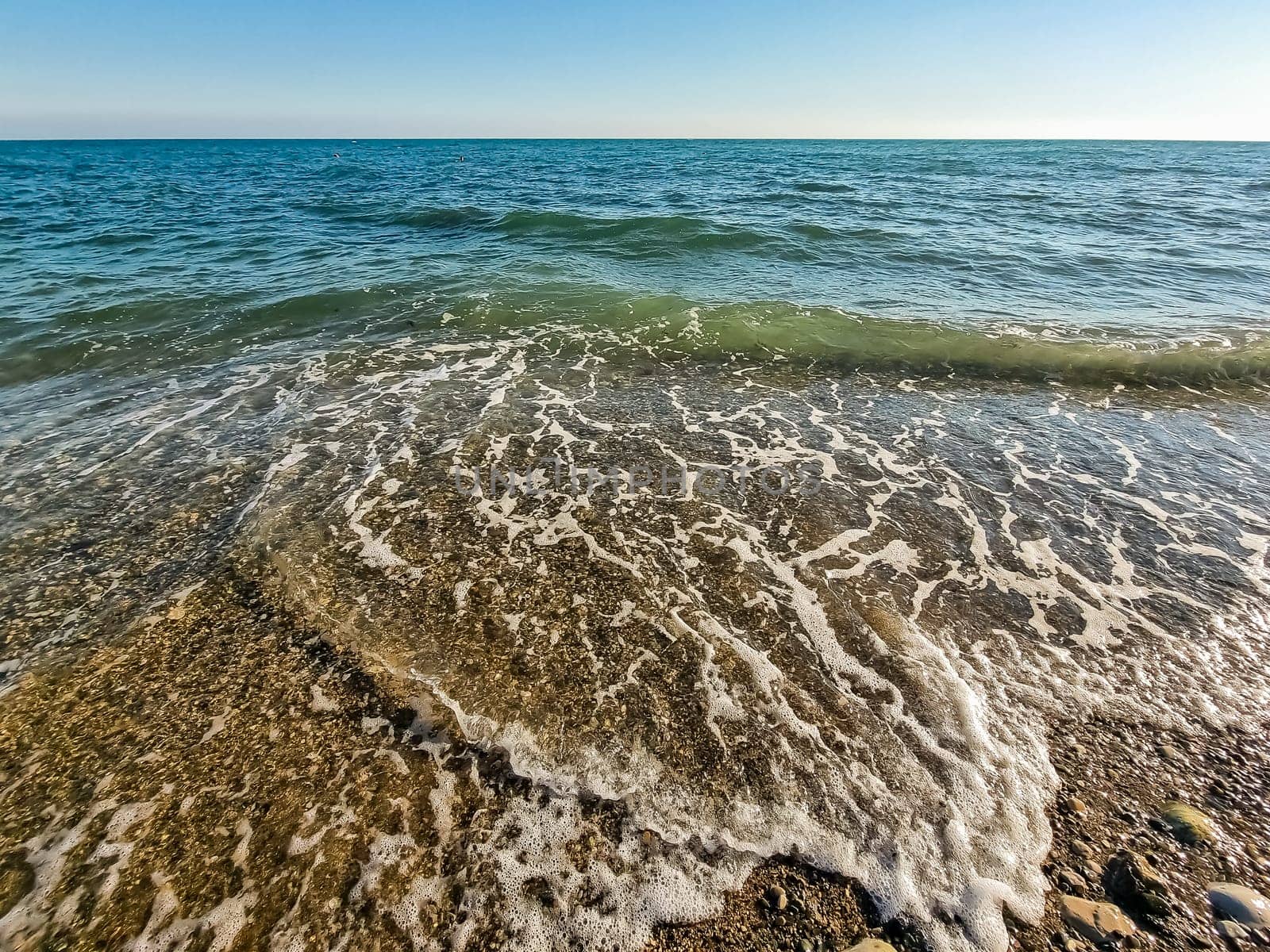 Scenic view of empty pebble sea coast during sunny day