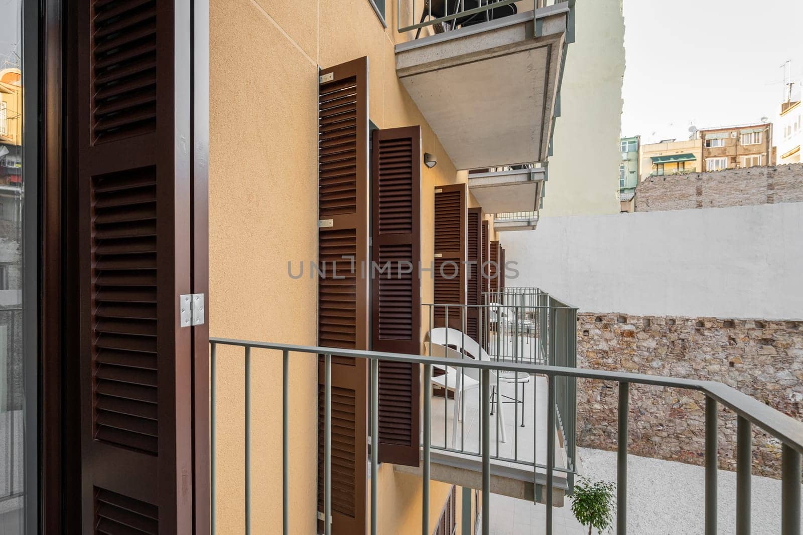 Access to an open loggia balcony in an apartment building with tables and chairs for a fresh air without leaving the house. The concept of comfortable modern housing.