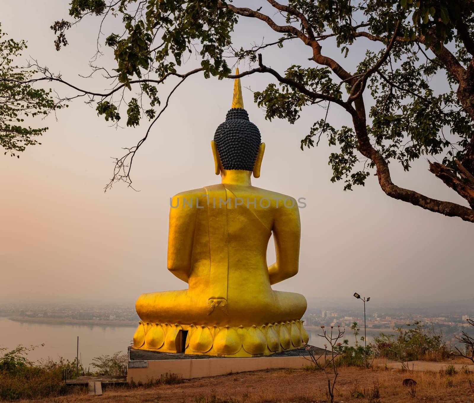 Golden Buddha overlooking Pakse at sunset. Wat Phousalao. Laos
