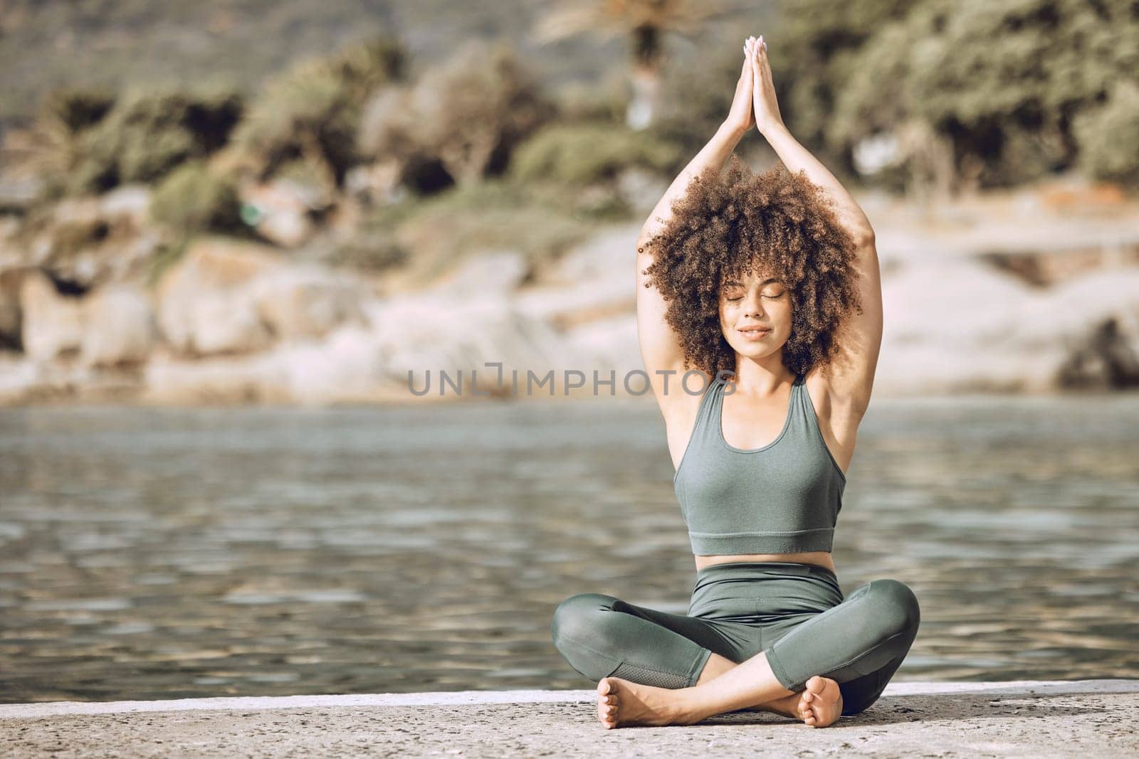 Yoga, meditation and calm black woman outdoor by beach, river or lake for healthy, wellness or fitness lifestyle. Mental health, peace and inner healing girl meditate, spiritual and workout in nature.