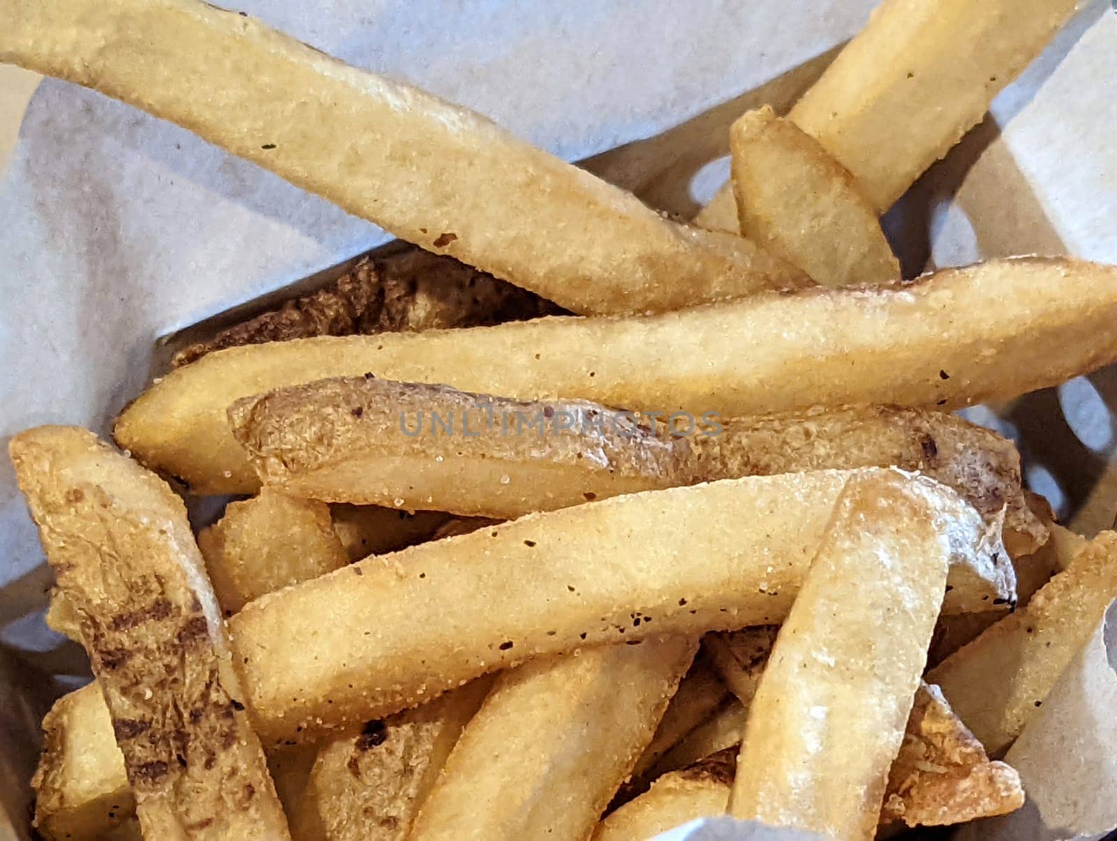 Close-up of asket filled with french fries on top of a table.