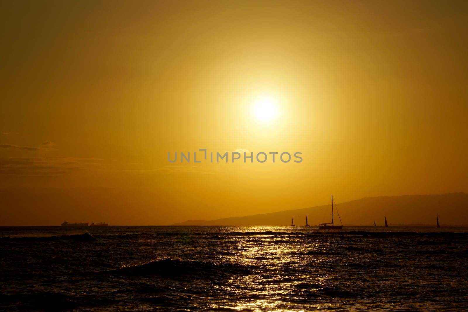 Captivating Sunset Over Waikiki Beach, Casting a Warm Glow on the Ocean with Graceful Boats Adorning the Water, Oahu, Hawaii.