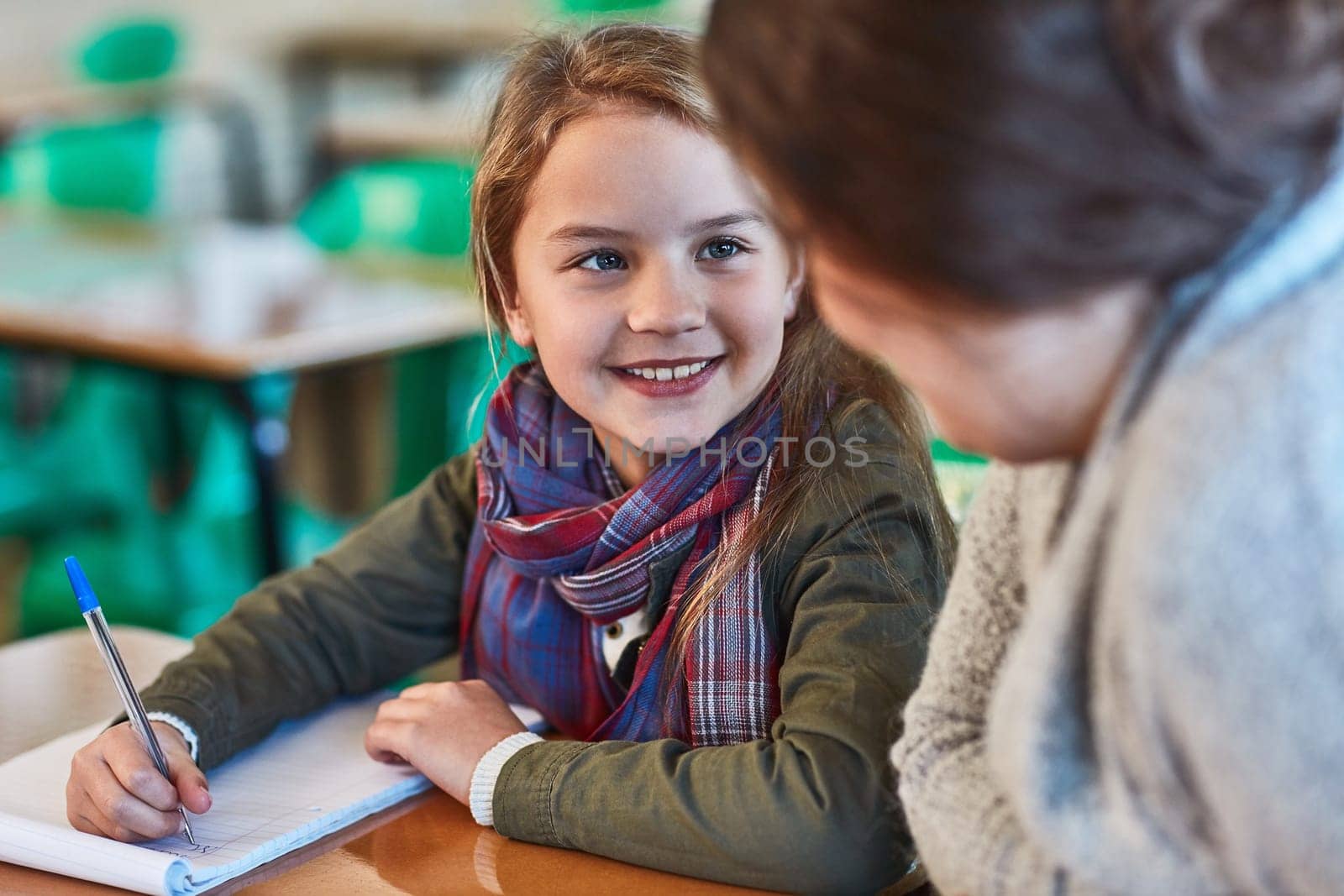 School, education and a student girl with her teacher in the classroom for learning or child development. Study, writing and smile with a happy young female pupil in class with a woman educator.