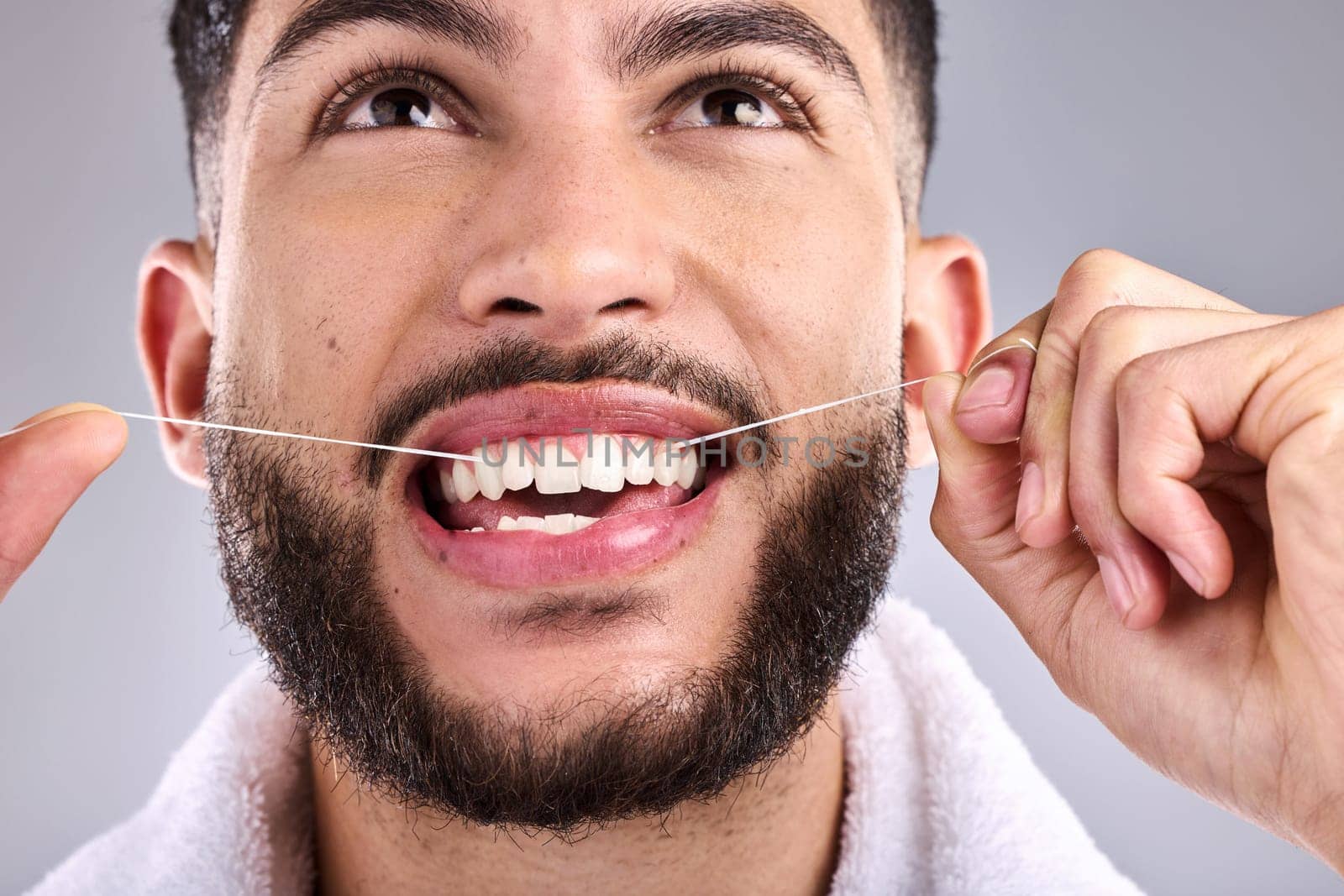 Face, dental and man floss teeth in studio isolated on a white background. Tooth, flossing product and male model cleaning for oral wellness, fresh breath and healthy hygiene to stop gingivitis. by YuriArcurs