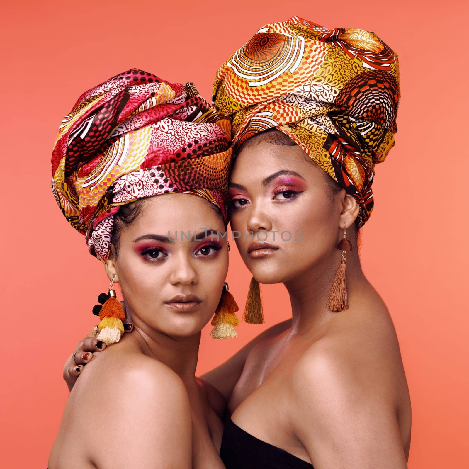 African fashion, makeup and portrait of women on orange background for cosmetics, beauty and accessory. Glamour, designer and face of female people in exotic jewelry, luxury style and scarf in studio.