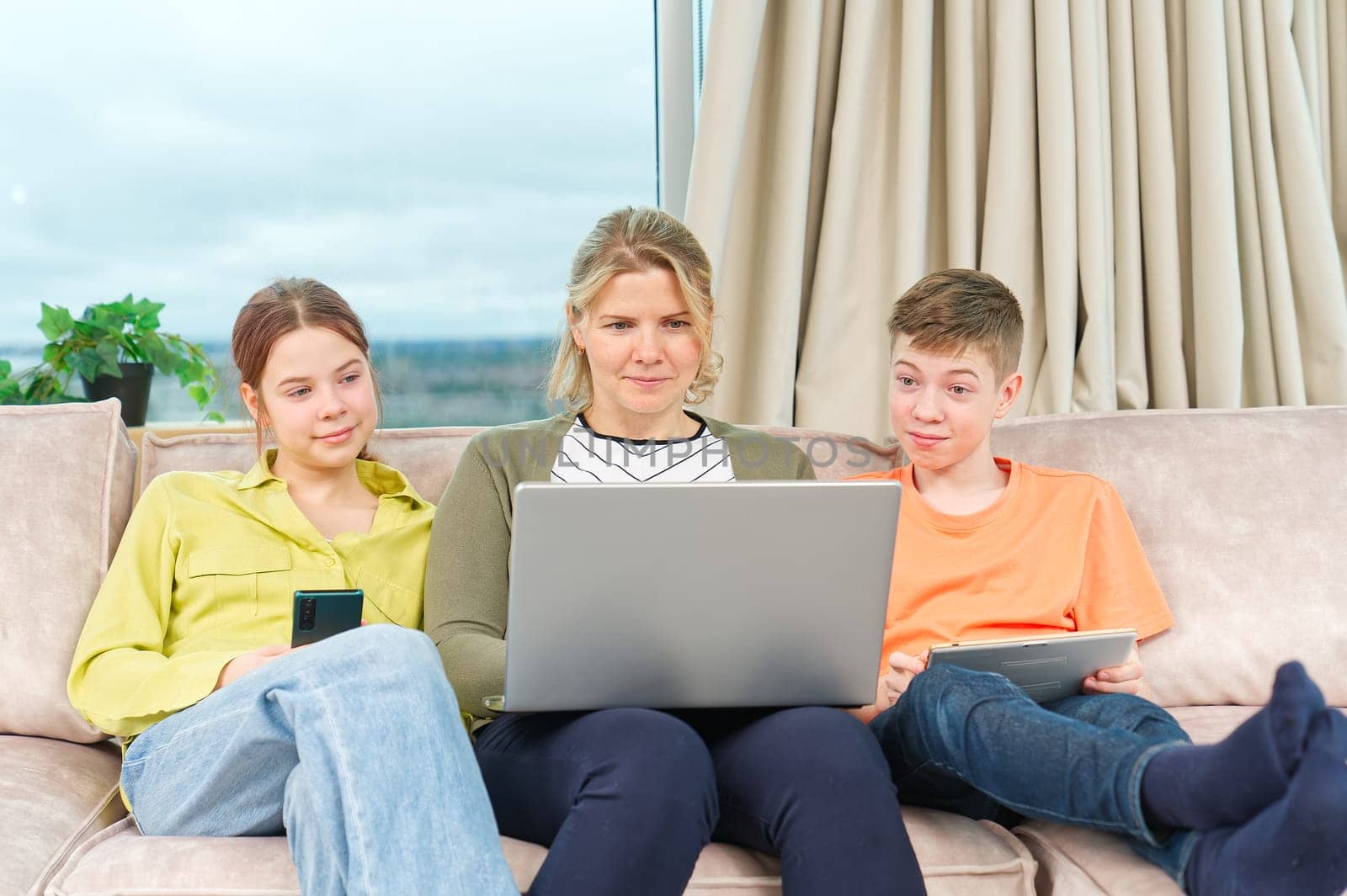 Happy Family on couch using gadget. Watching something online on computer together with family. Rest at home.