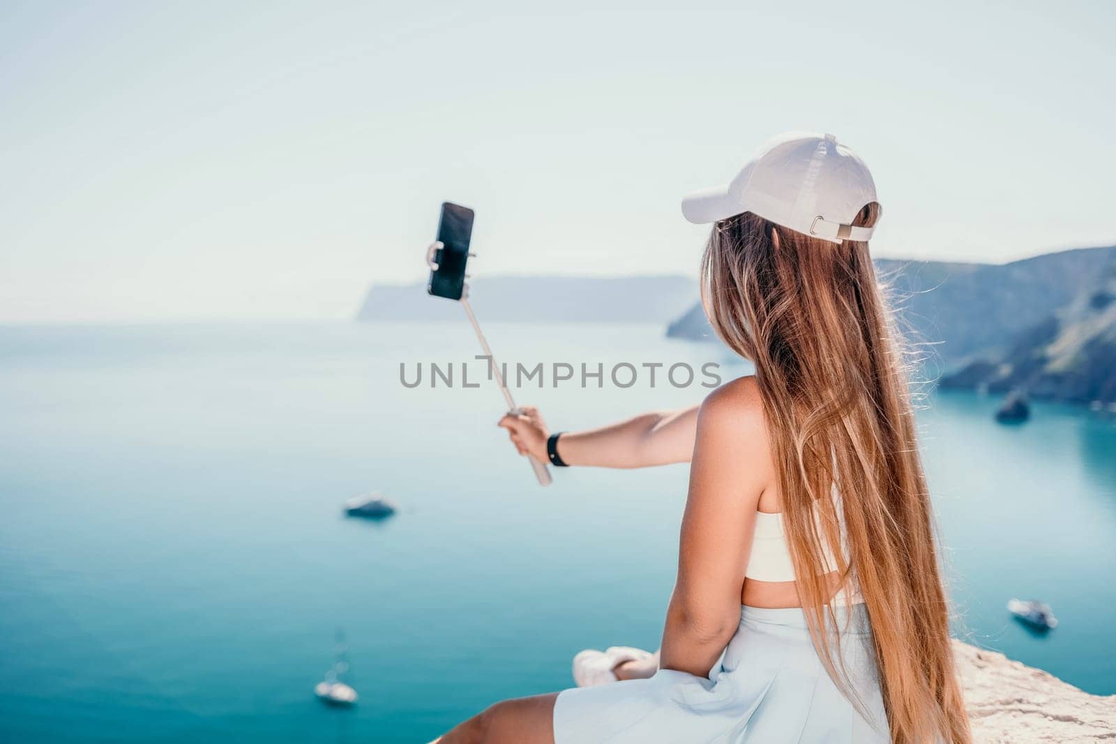 Digital nomad, Business woman working on laptop by the sea. Pretty lady typing on computer by the sea at sunset, makes a business transaction online from a distance. Freelance, remote work on vacation by panophotograph