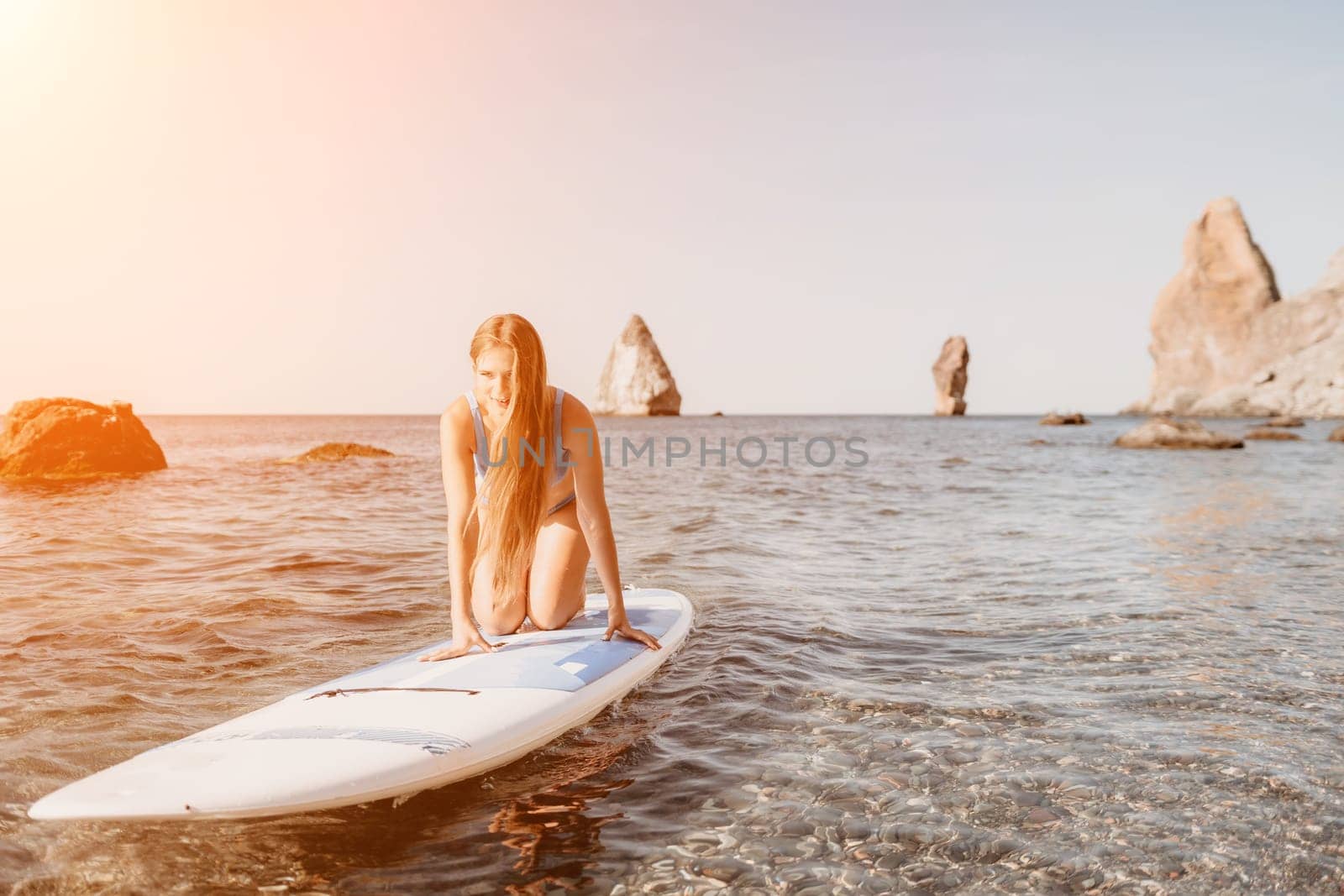 Woman sea sup. Close up portrait of happy young caucasian woman with long hair looking at camera and smiling. Cute woman portrait in a blue bikini posing on sup board in the sea by panophotograph