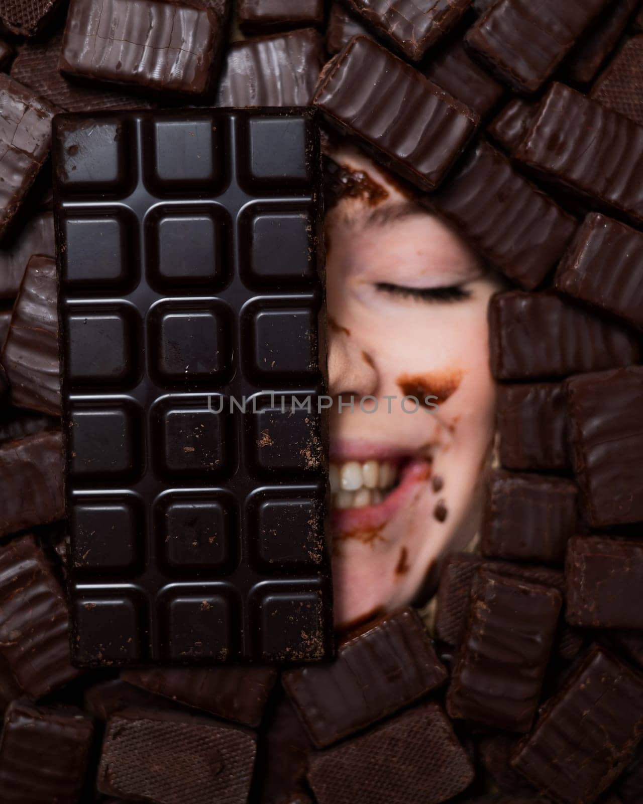 The face of a caucasian woman surrounded by sweets. The girl is smeared in chocolate