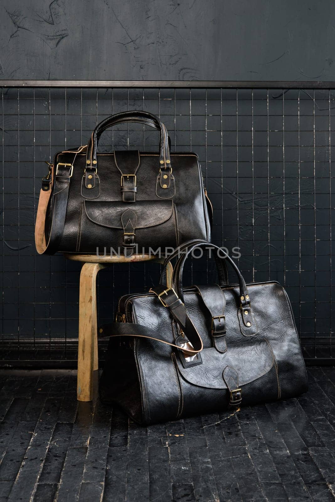 two different size black leather travel bags, indoors photo on black background