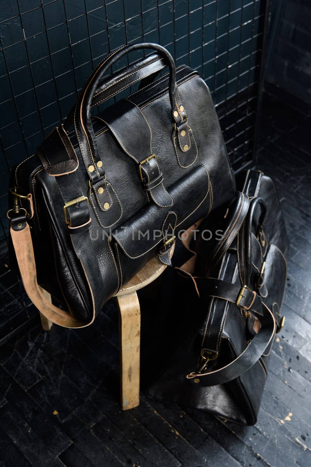 two different size black leather travel bags, indoors photo on black background