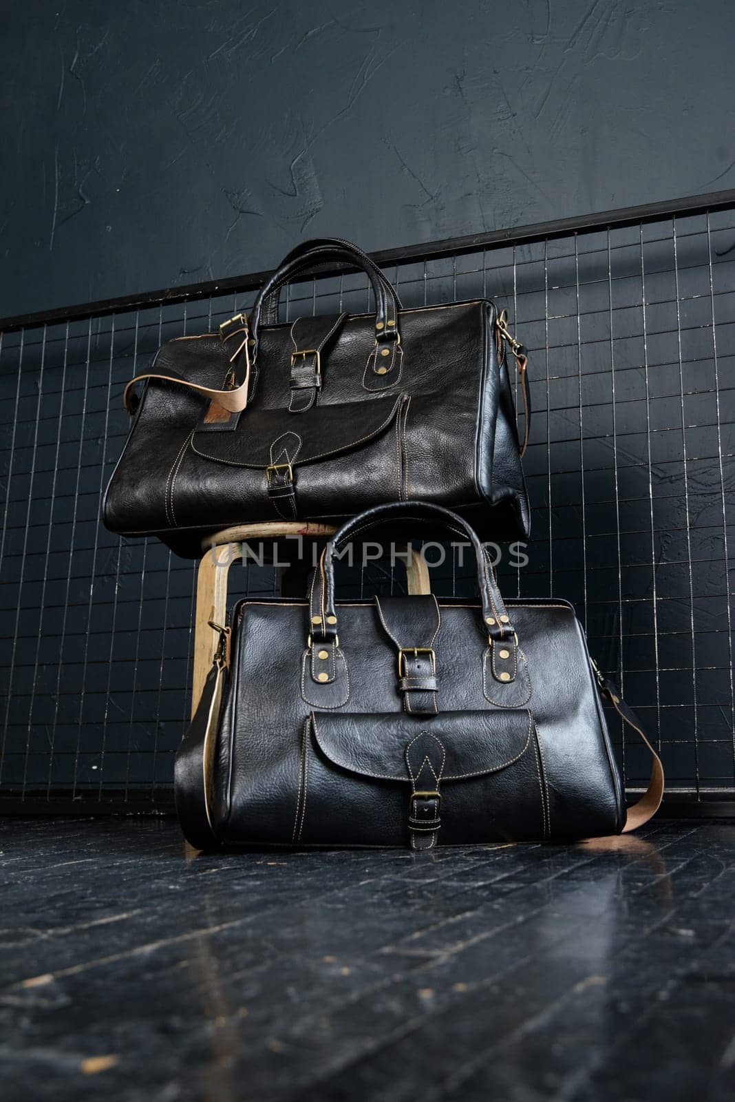 two different size black leather travel bags, indoors photo on black background