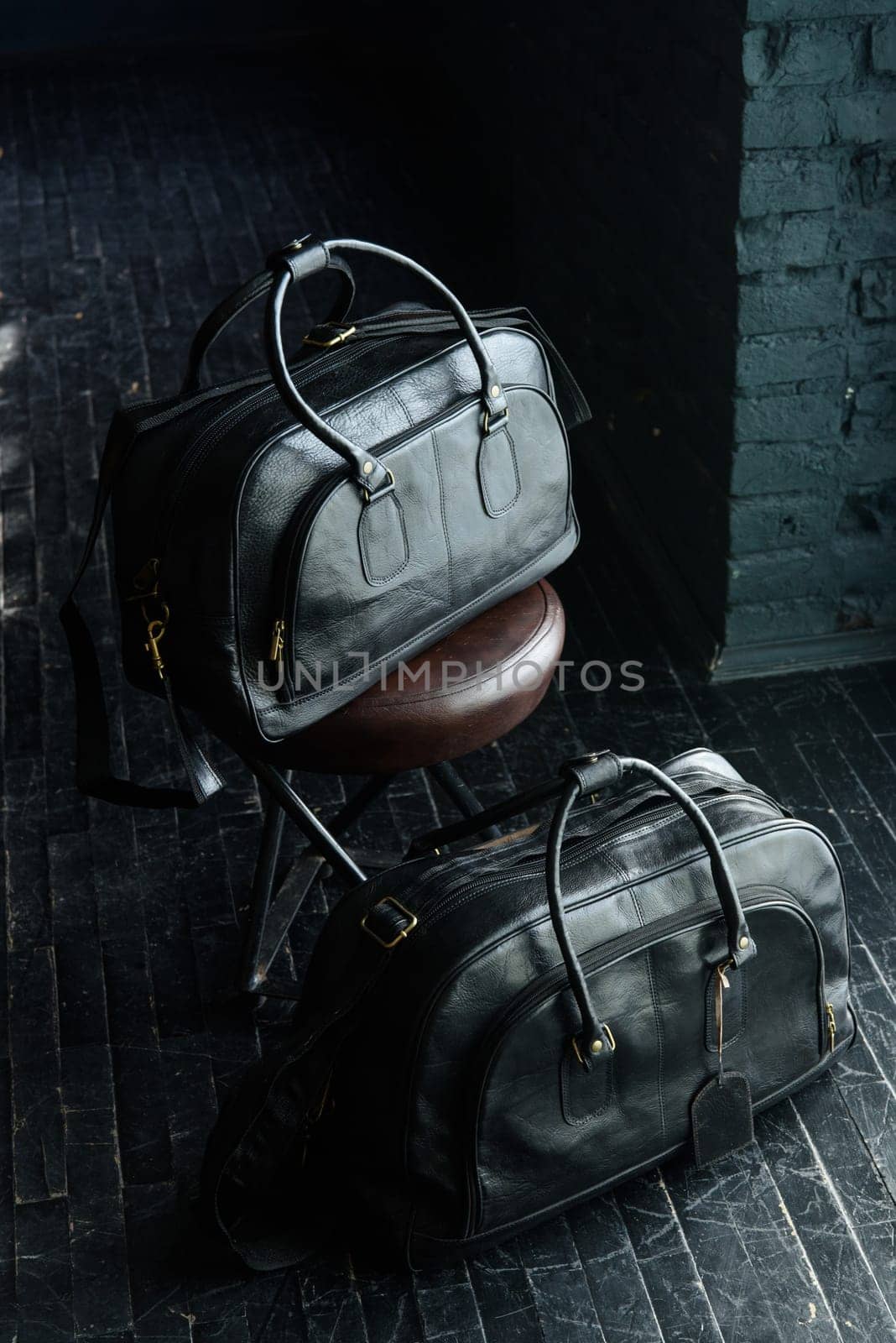 two different size black leather travel bags, indoors photo on black background