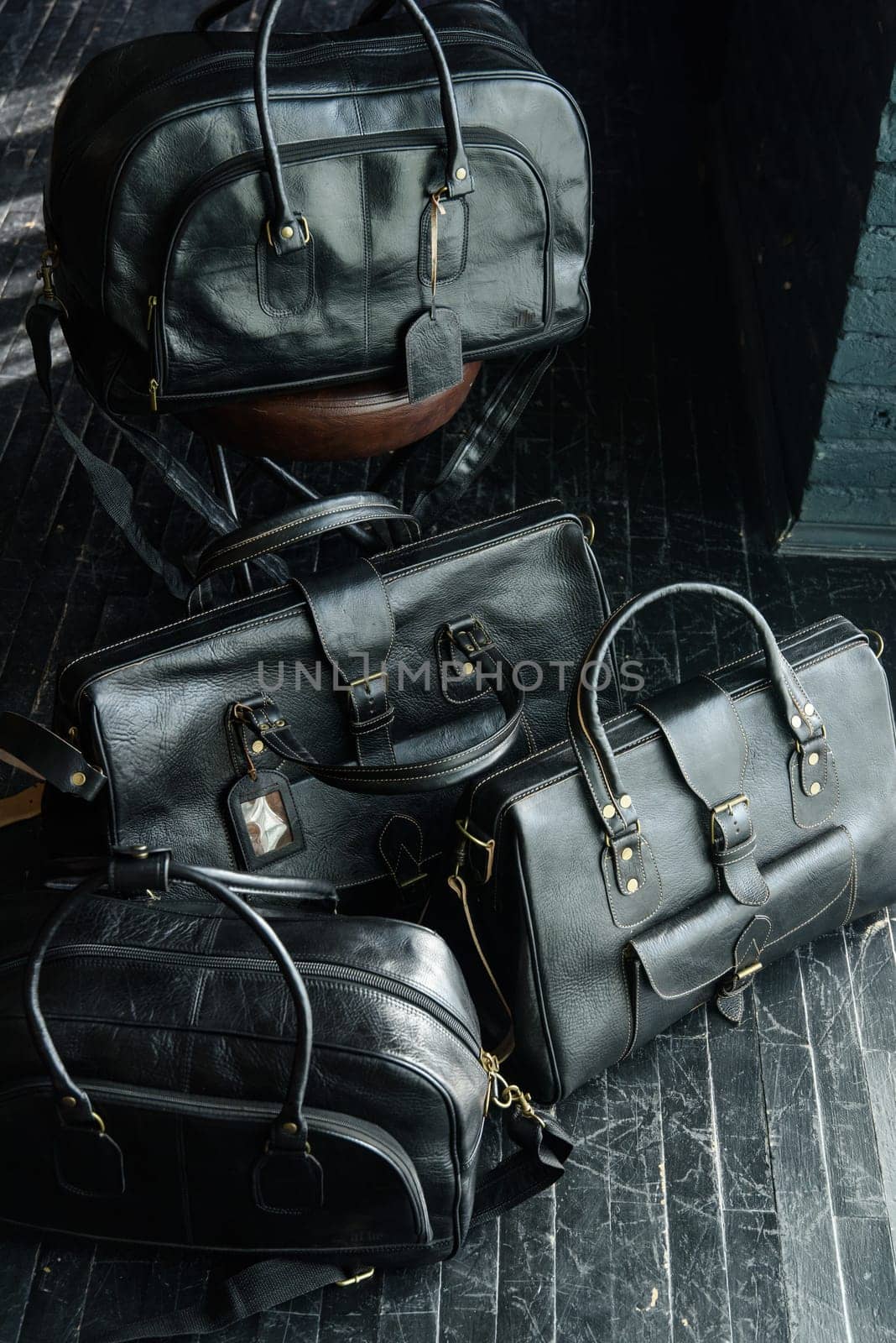 four different size and shape black leather travel bags, indoors photo on black background