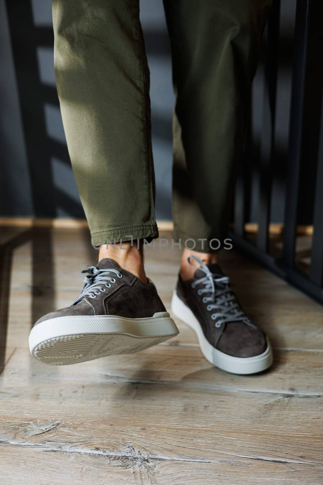 Close-up of male legs in pants and gray casual sneakers. Men's leather shoes. Collection of men's stylish summer shoes