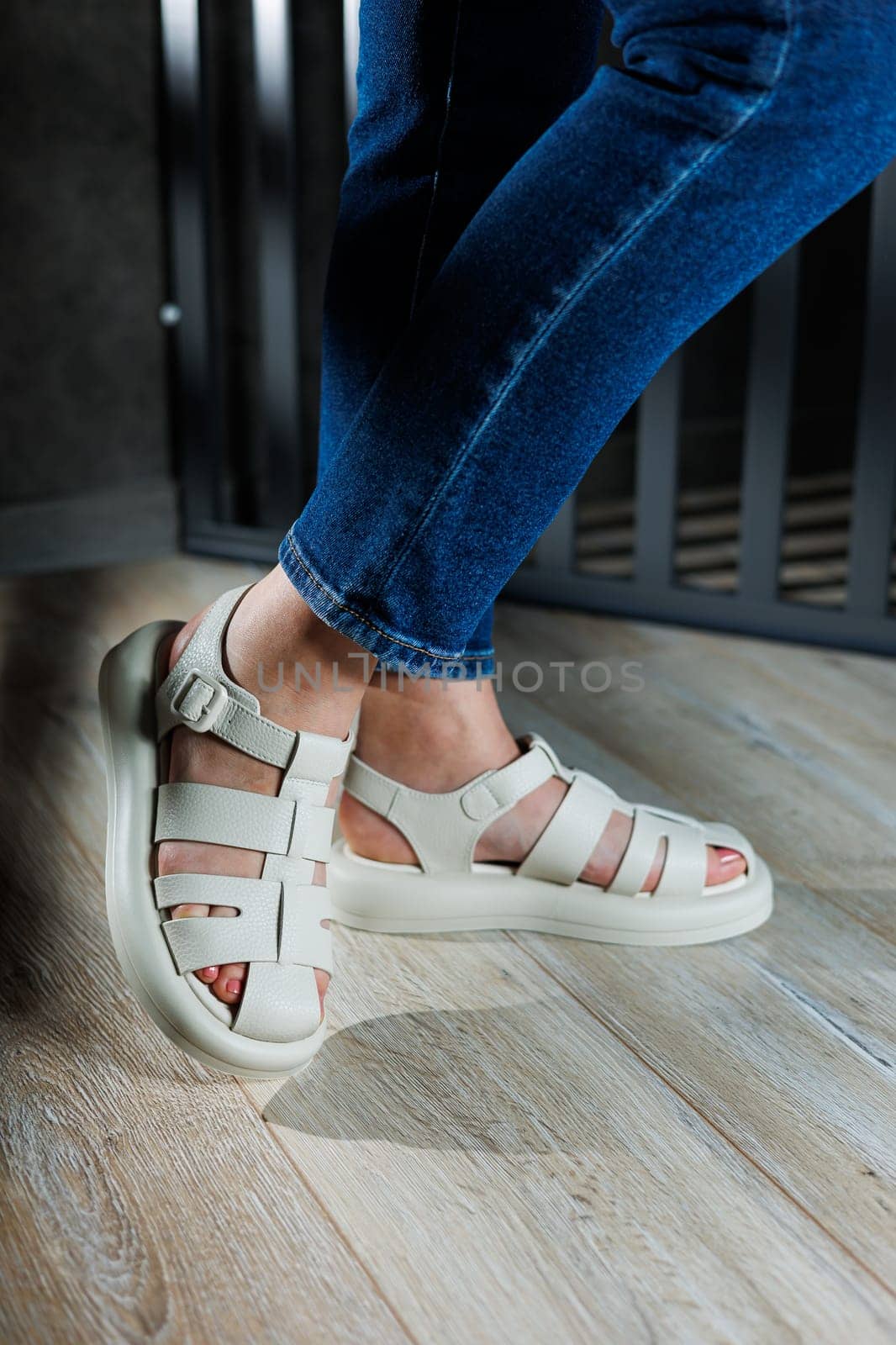 Slender female legs in beige leather sandals without heels. Collection of women's summer sandals.