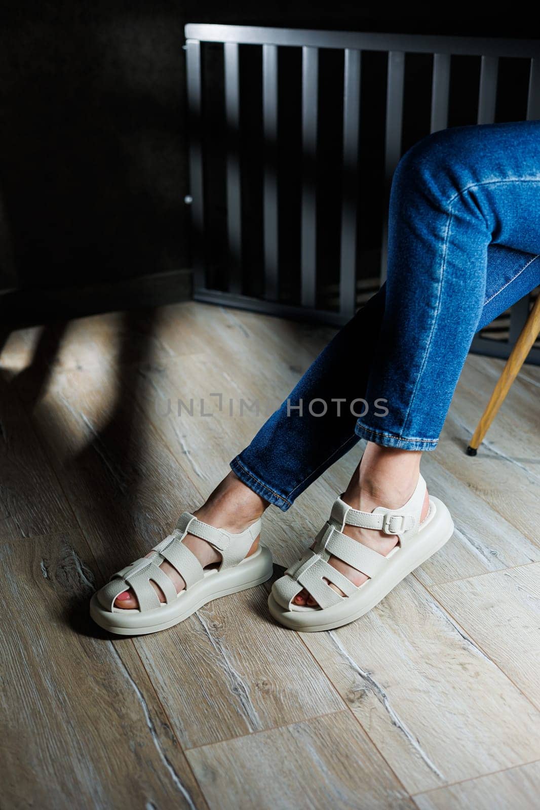 Slender female legs in beige leather sandals without heels. Collection of women's summer sandals.