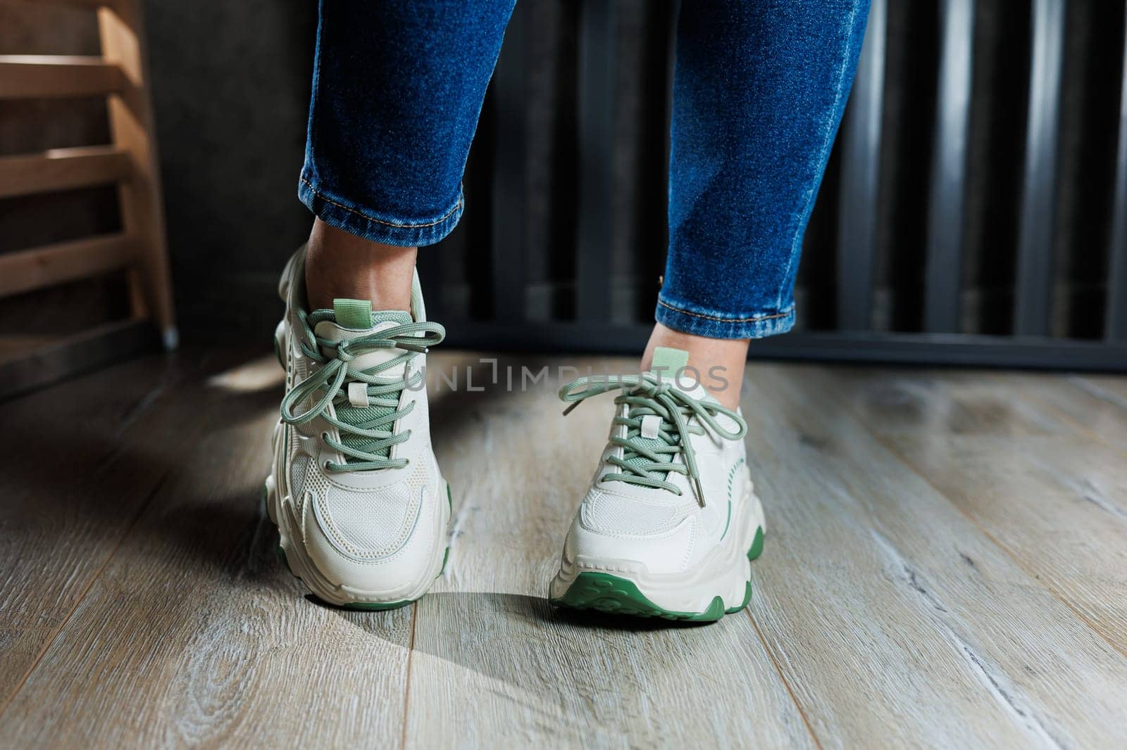 White leather summer sneakers on female legs in jeans. Women's casual sneakers. Comfortable women's shoes