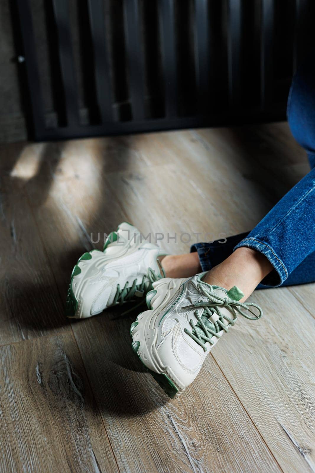 Sports shoes for women. Slender female legs in jeans and white stylish casual sneakers. Comfortable women's summer shoes. Casual women's fashion.